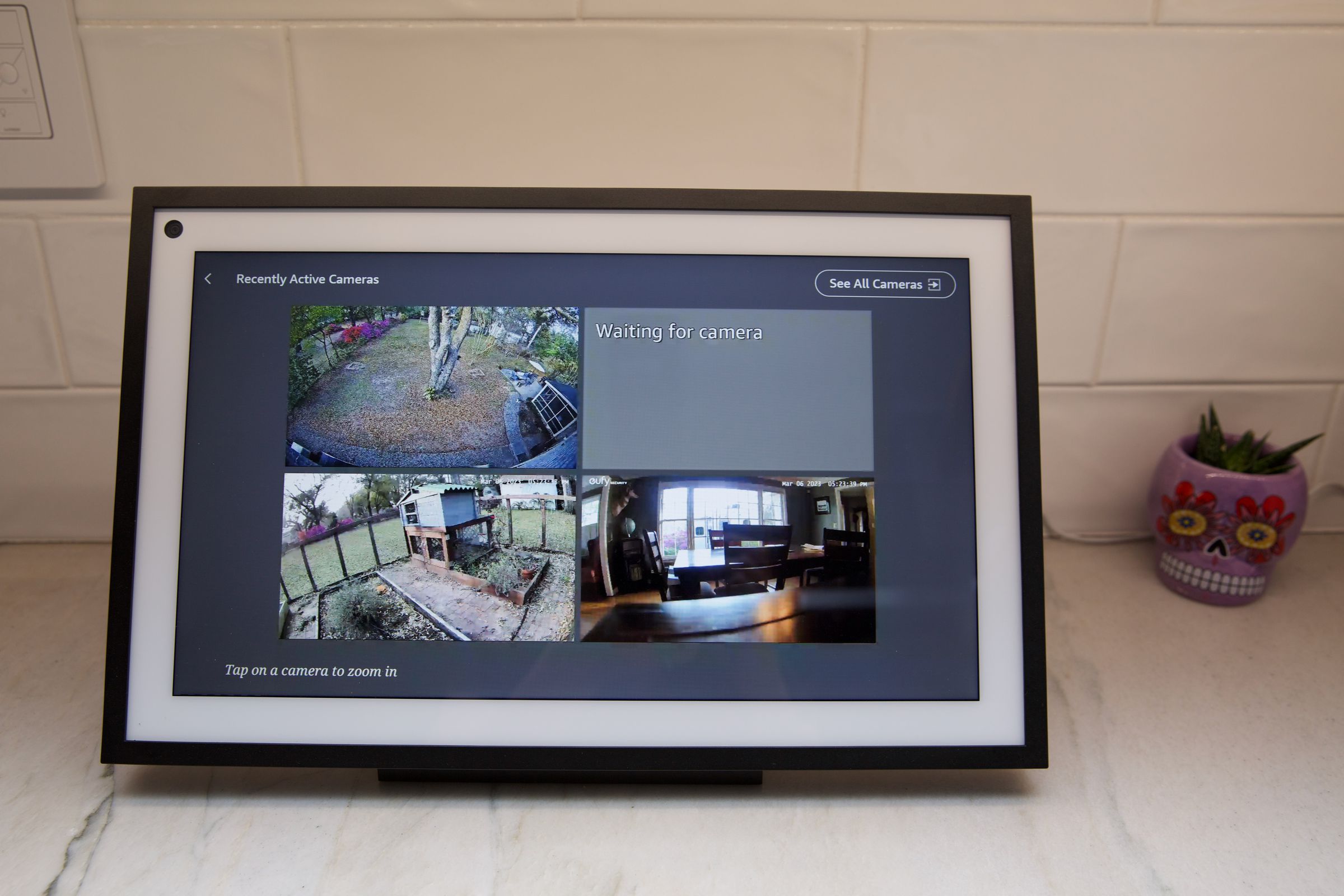 An Echo Show 15 displaying multiple live feeds from three security cameras, including Eufy and Google Nest cameras.