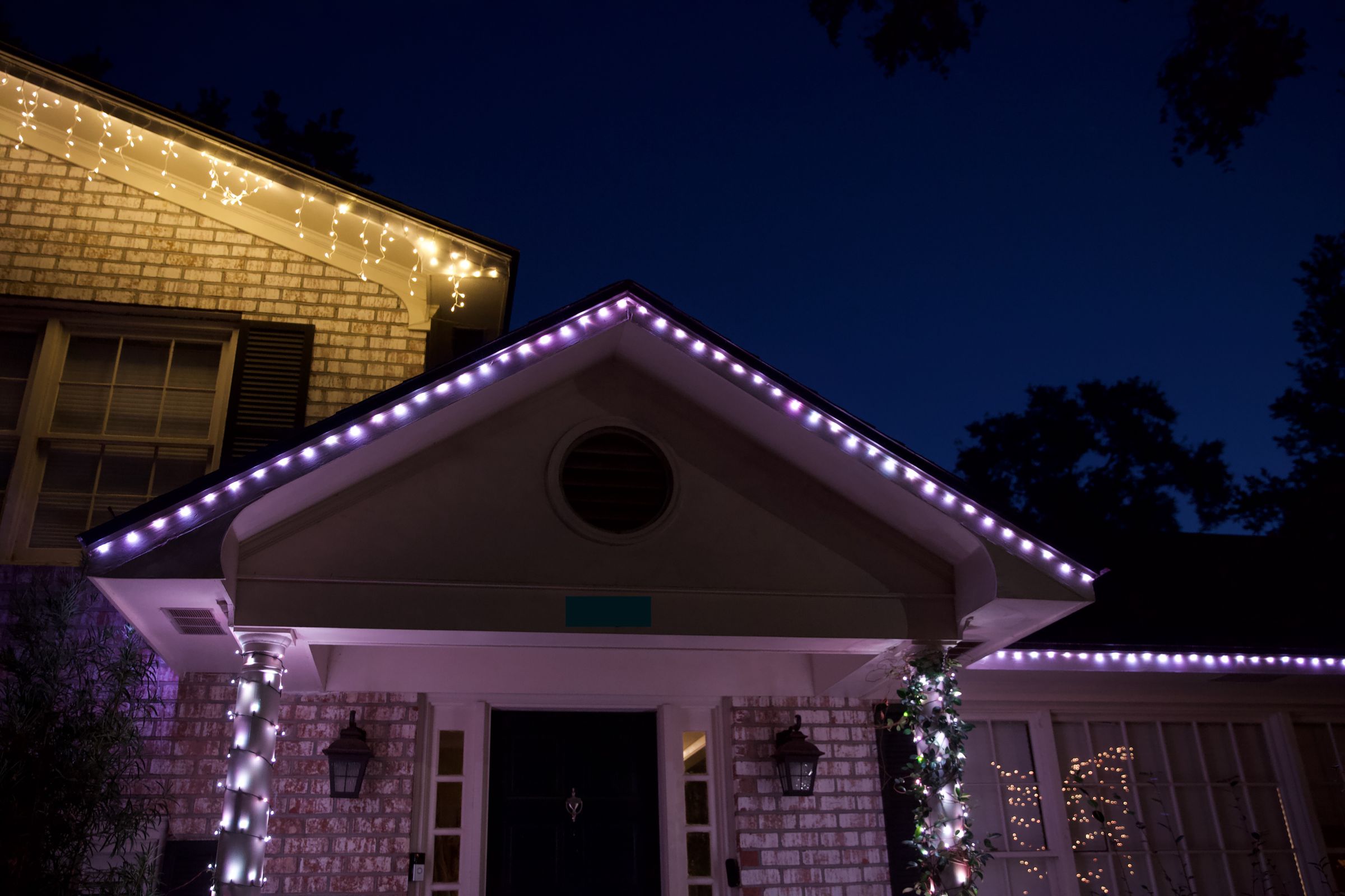 The Govee lights on the porch peak and the roofline to the right are drop heads. They have a flatter, wider look than traditional bullet-head string lights like the Twinkly strands on the columns.