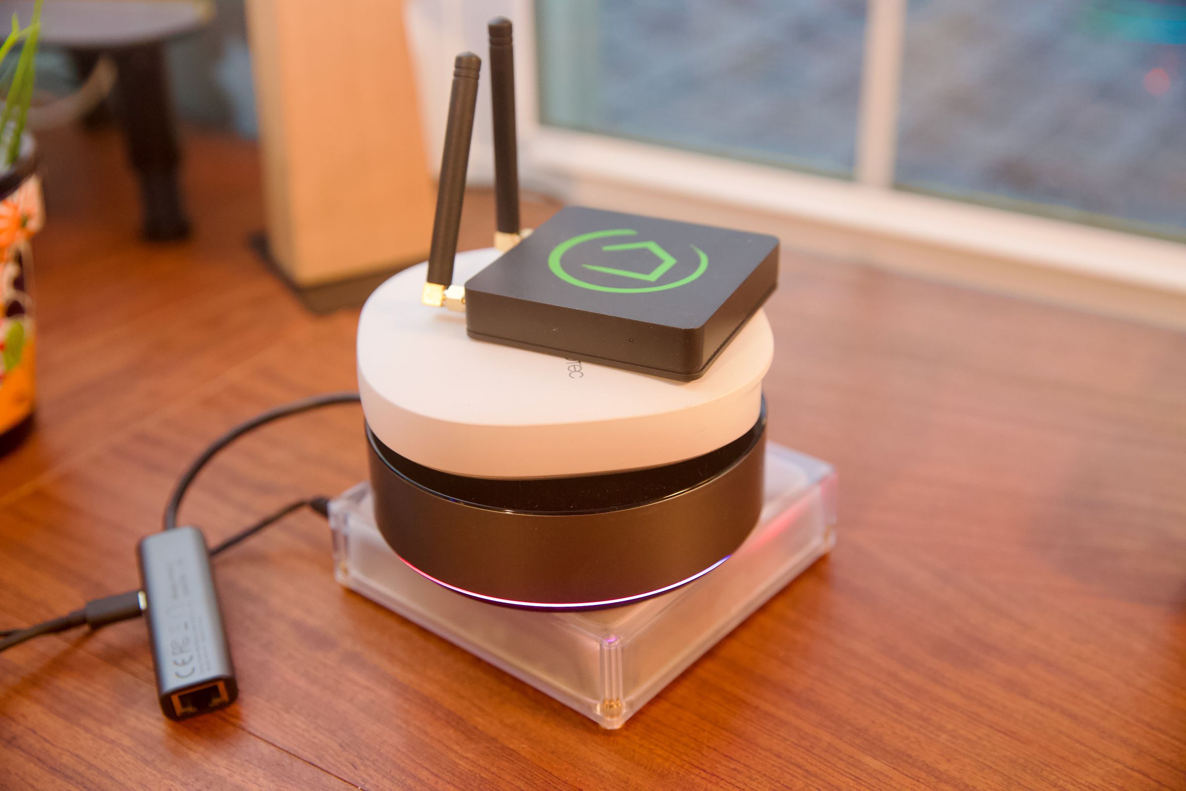 Four smart home hubs stacked on a wooden desk.