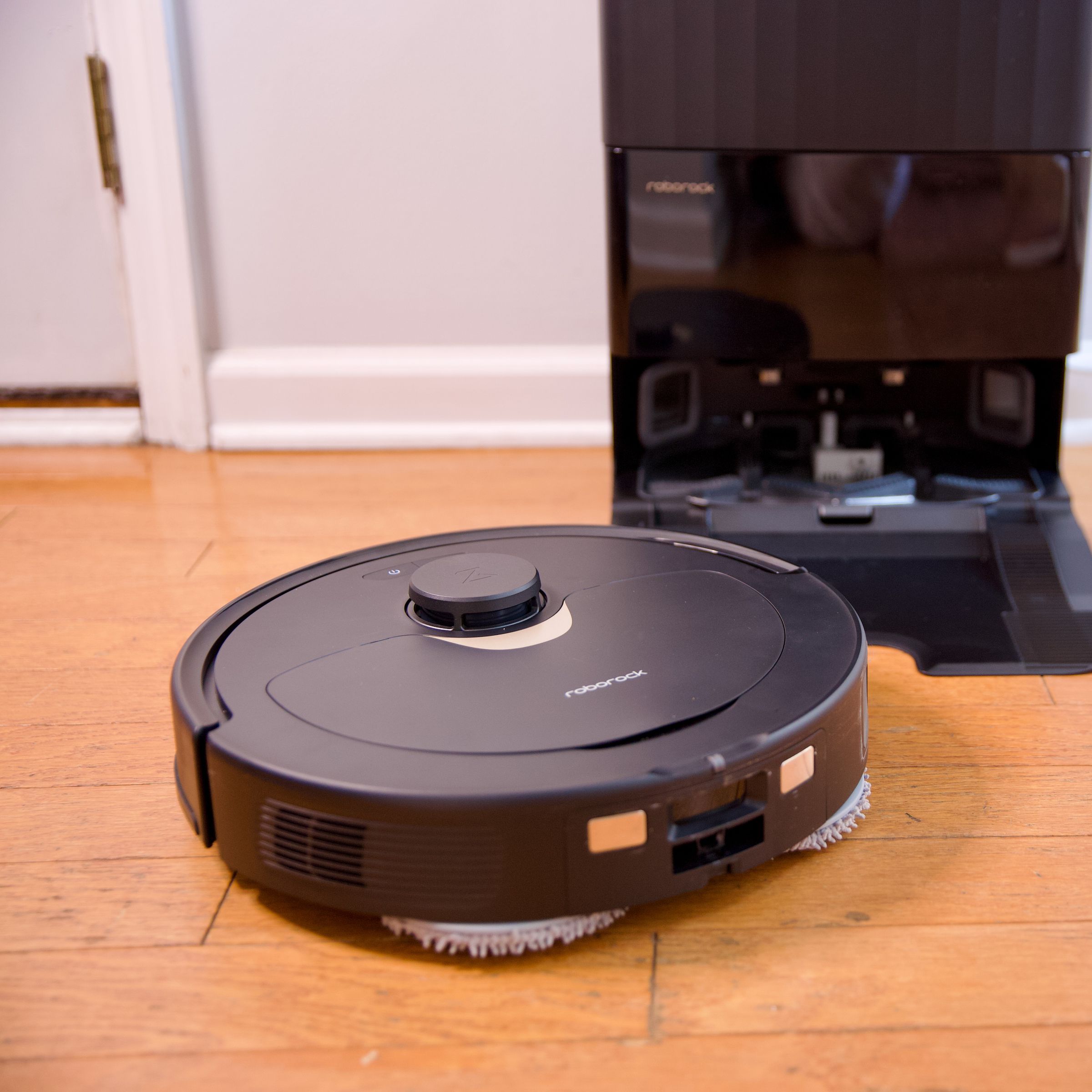 Roborock’s Q Revo robot vacuum sitting on a hardwood floor with its charging dock.