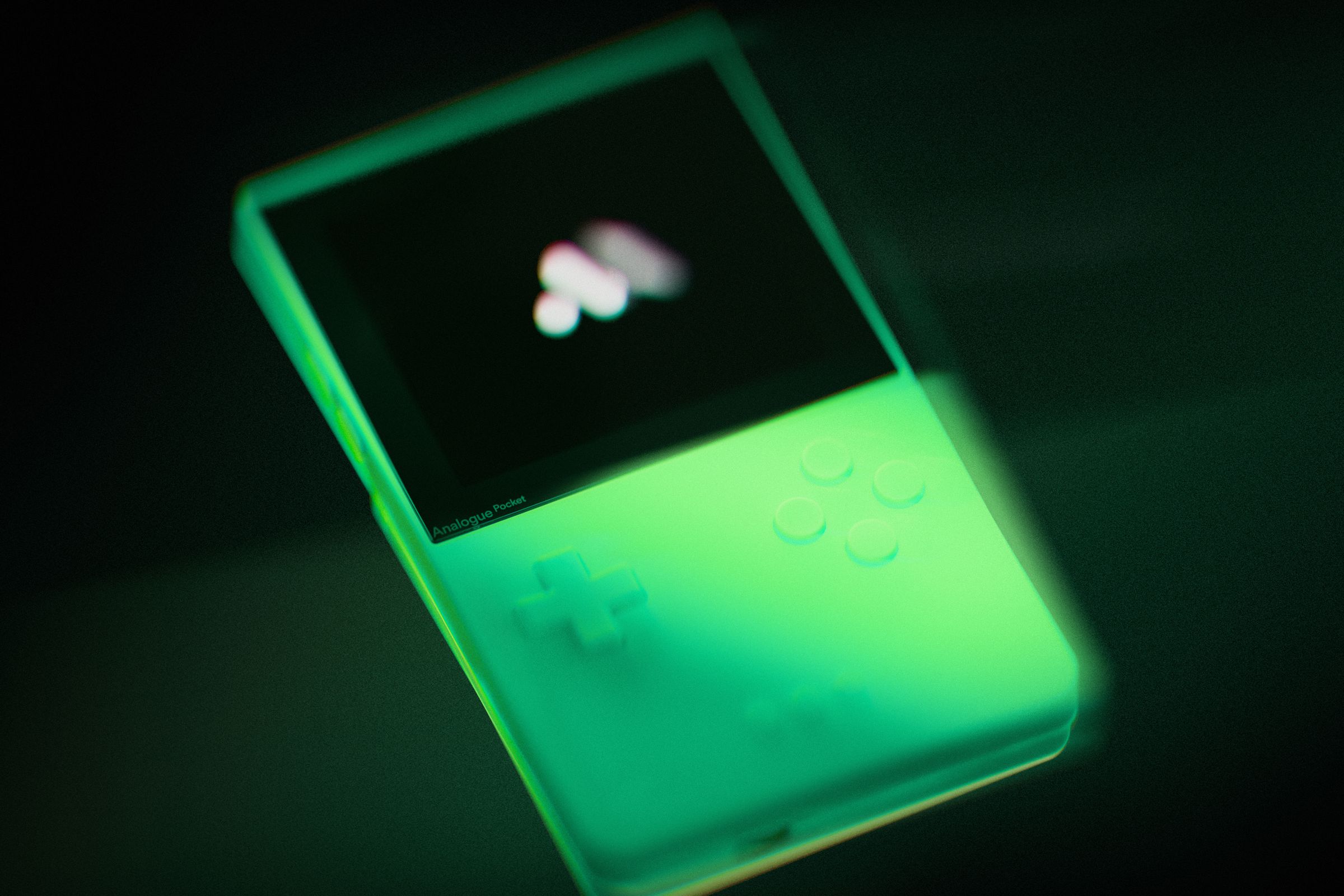 A photo of a glow in the dark Analogue Pocket gaming handheld.