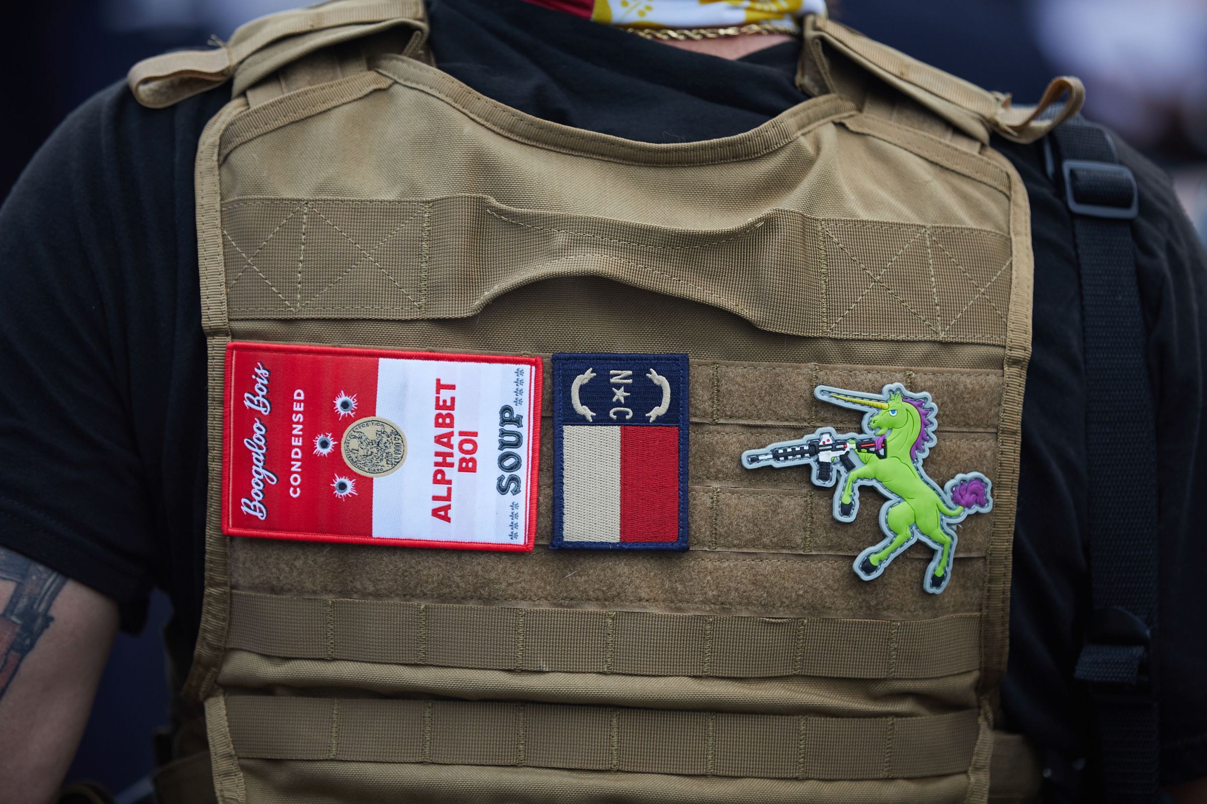 A member of the far-right militia, Boogaloo Bois, walks next to protestors demonstrating outside Charlotte Mecklenburg Police Department Metro Division 2 just outside of downtown Charlotte, North Carolina, on May 29, 2020