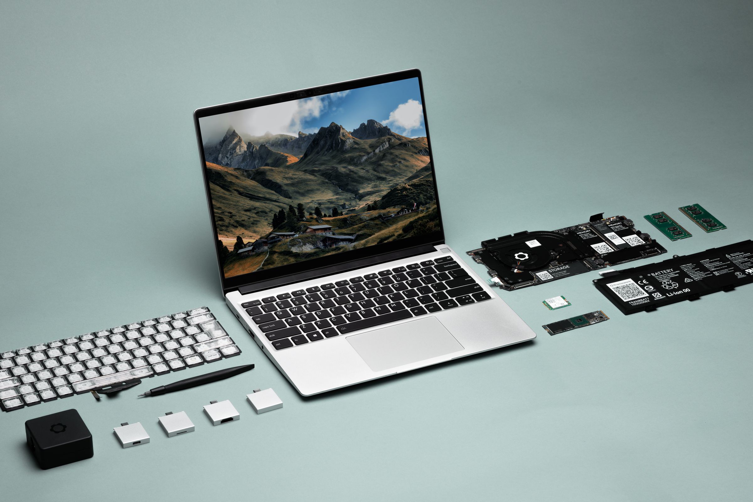 A Framework Laptop angled slightly to the right, seen from above. The screen displays mountains and a valley. On either side are a number of modules.
