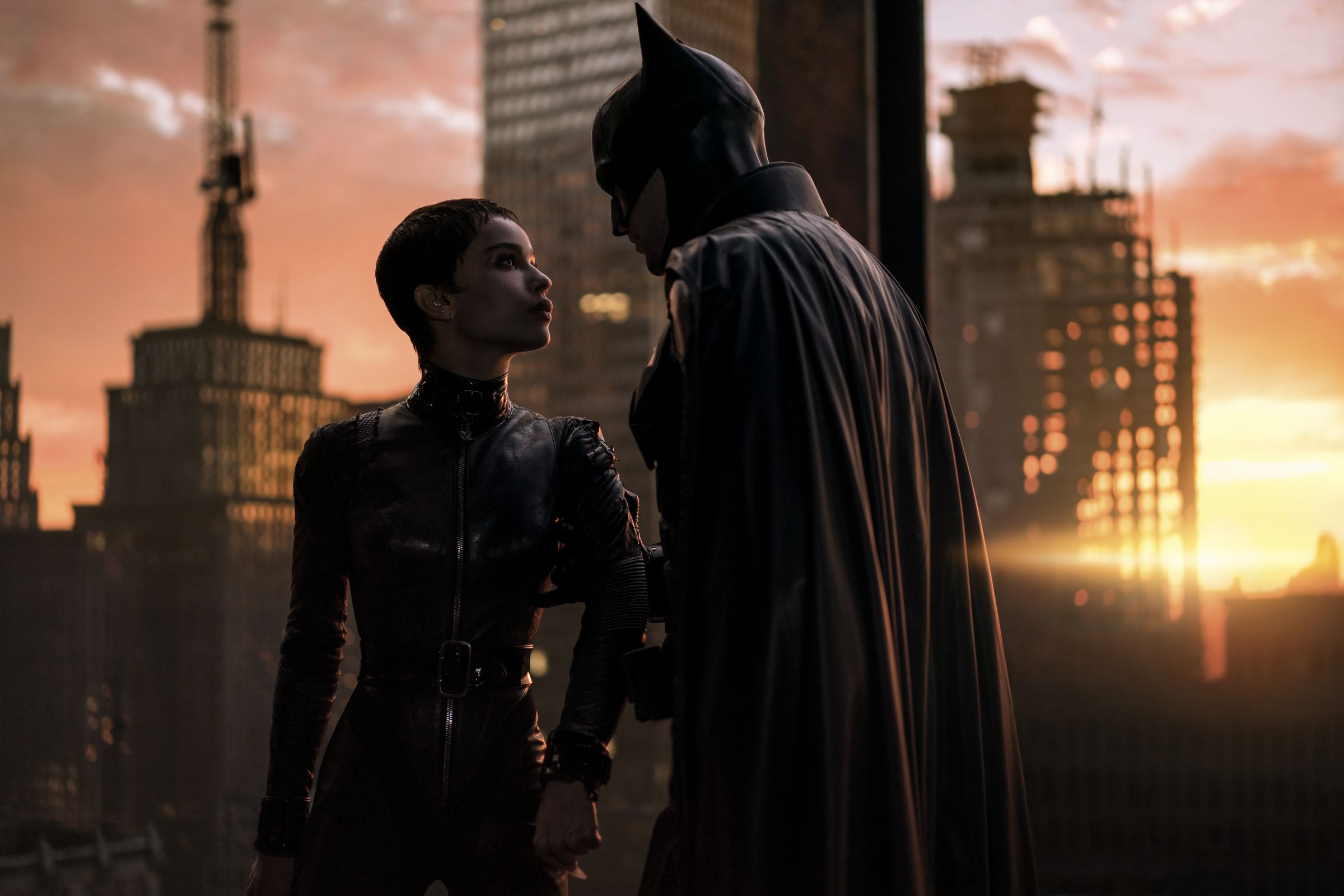 Selina Kyle and Batman atop a skyscraper disagreeing about how to handle criminals.