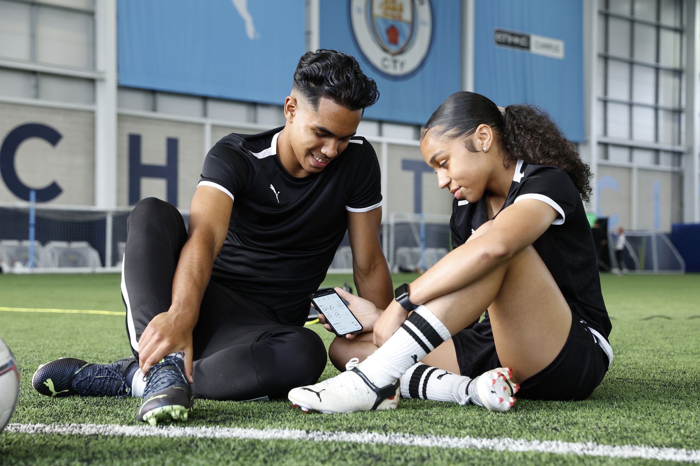 Two players looking at their phone while wearing the Cityplay tracker on their shoes.