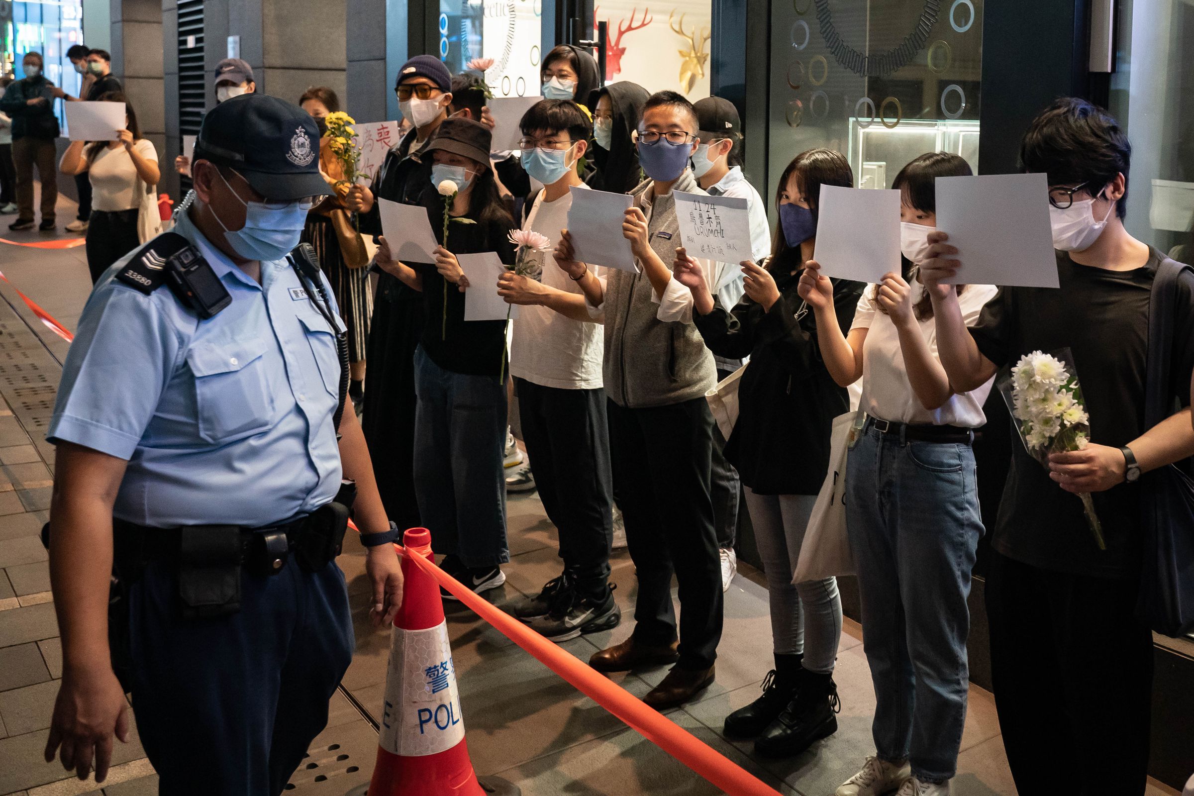 People in Hong Kong protest in a line while holding blank white sheets of paper.