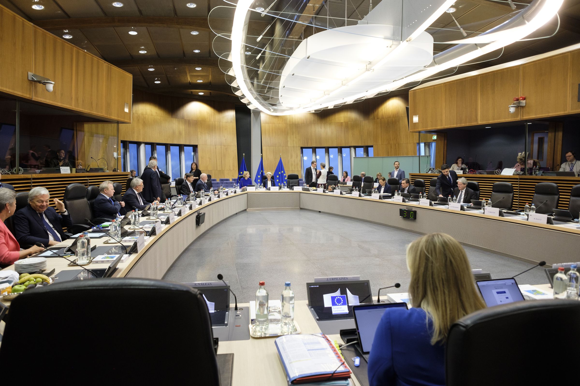 Members of the EU Commission sit around tables inside a meeting room.