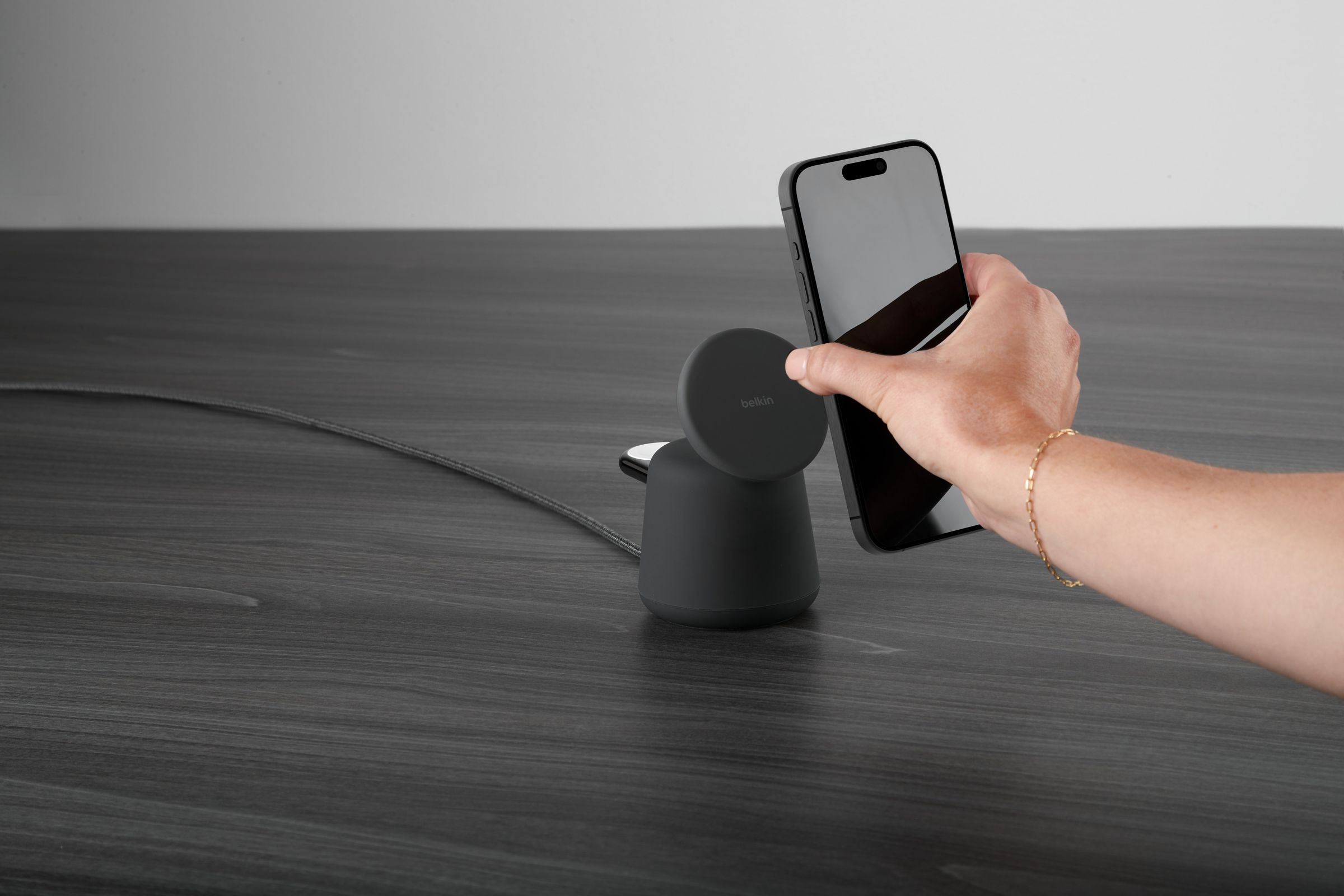 A photo of a person bringing an iPhone toward Belkin’s new charging dock.