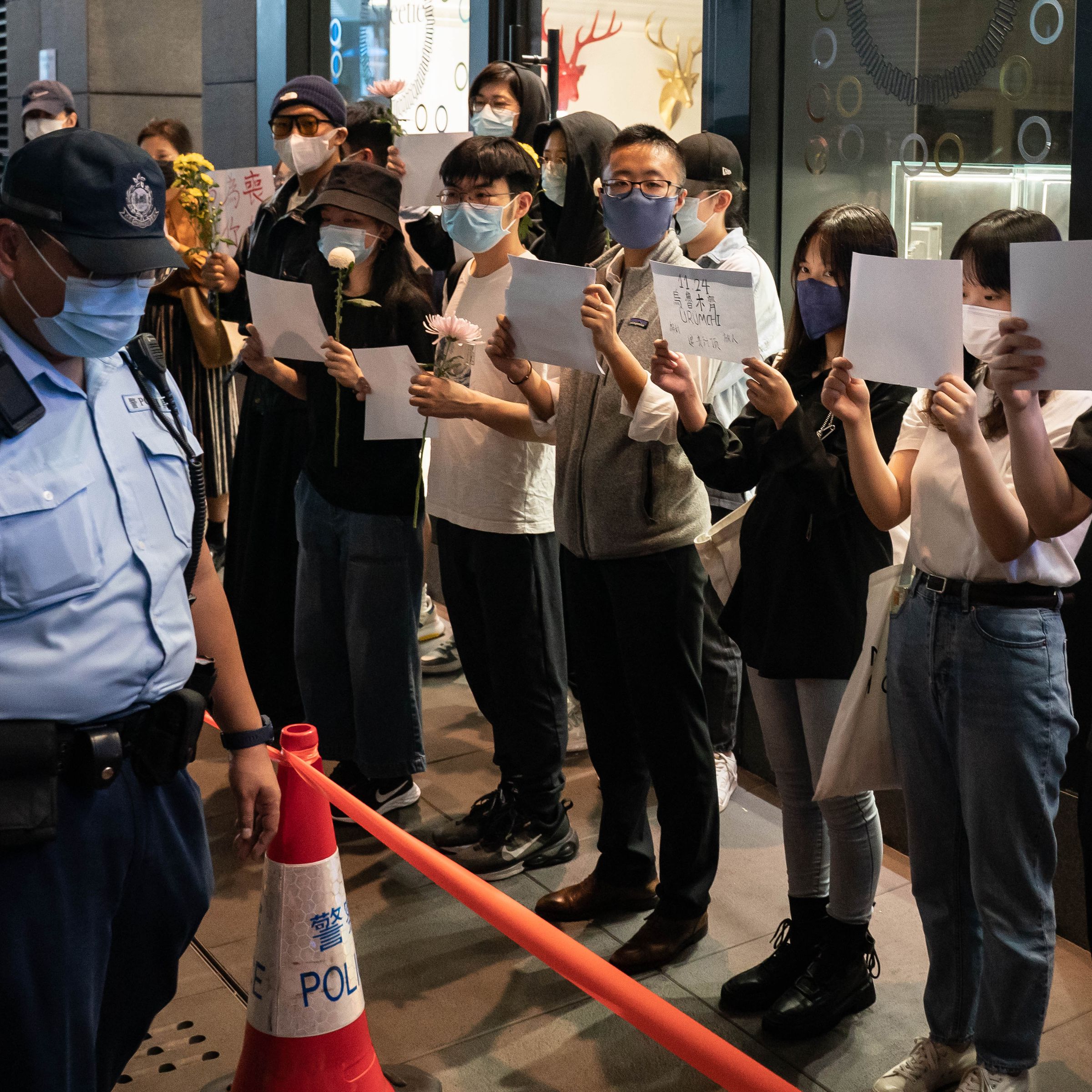 People in Hong Kong protest in a line while holding blank white sheets of paper.