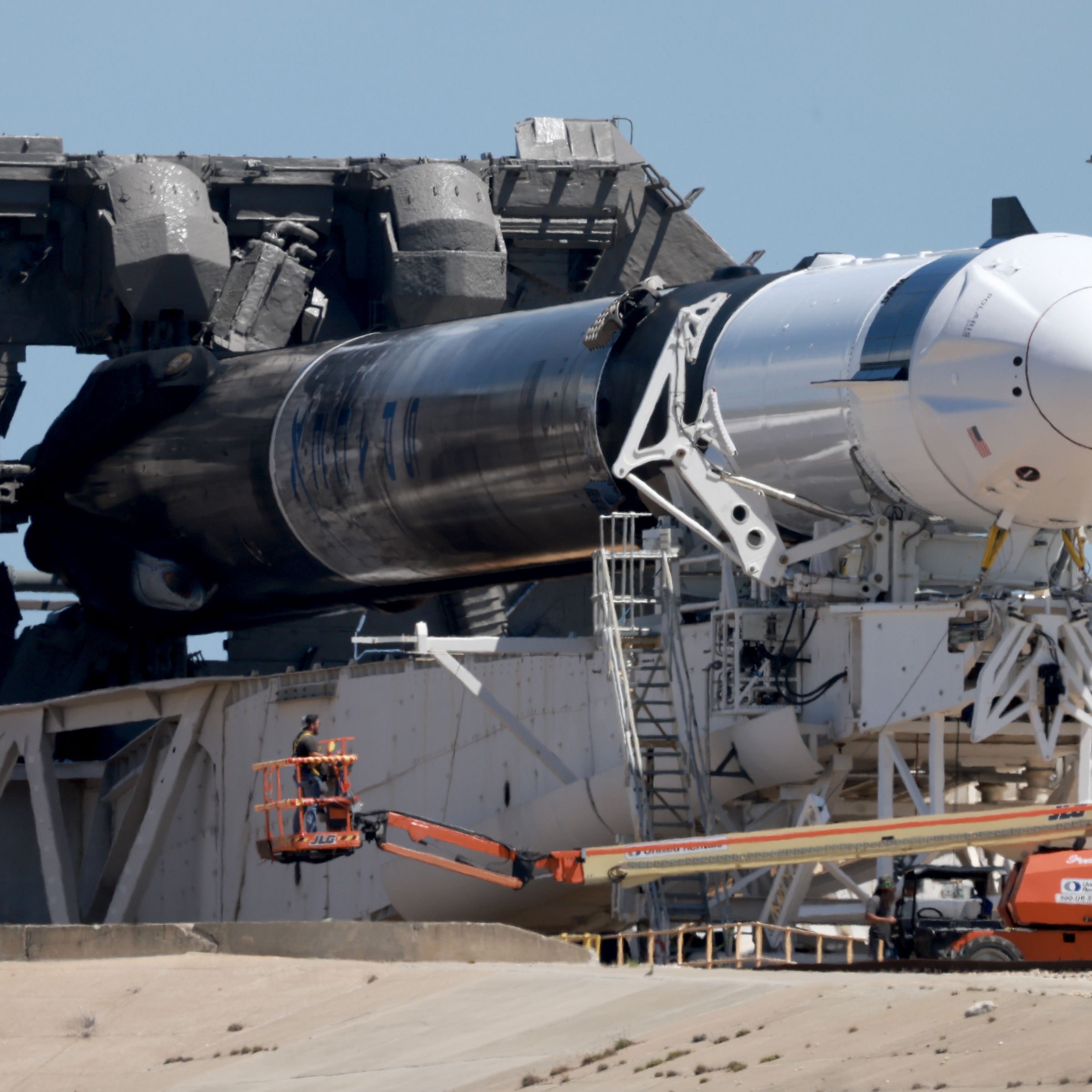 A Falcon 9 rocket, turned sideways while workers prepare it for a new mission.