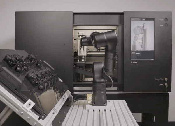 A robot arm pulls items in and out of the CT scanner, door automatically opening each time.