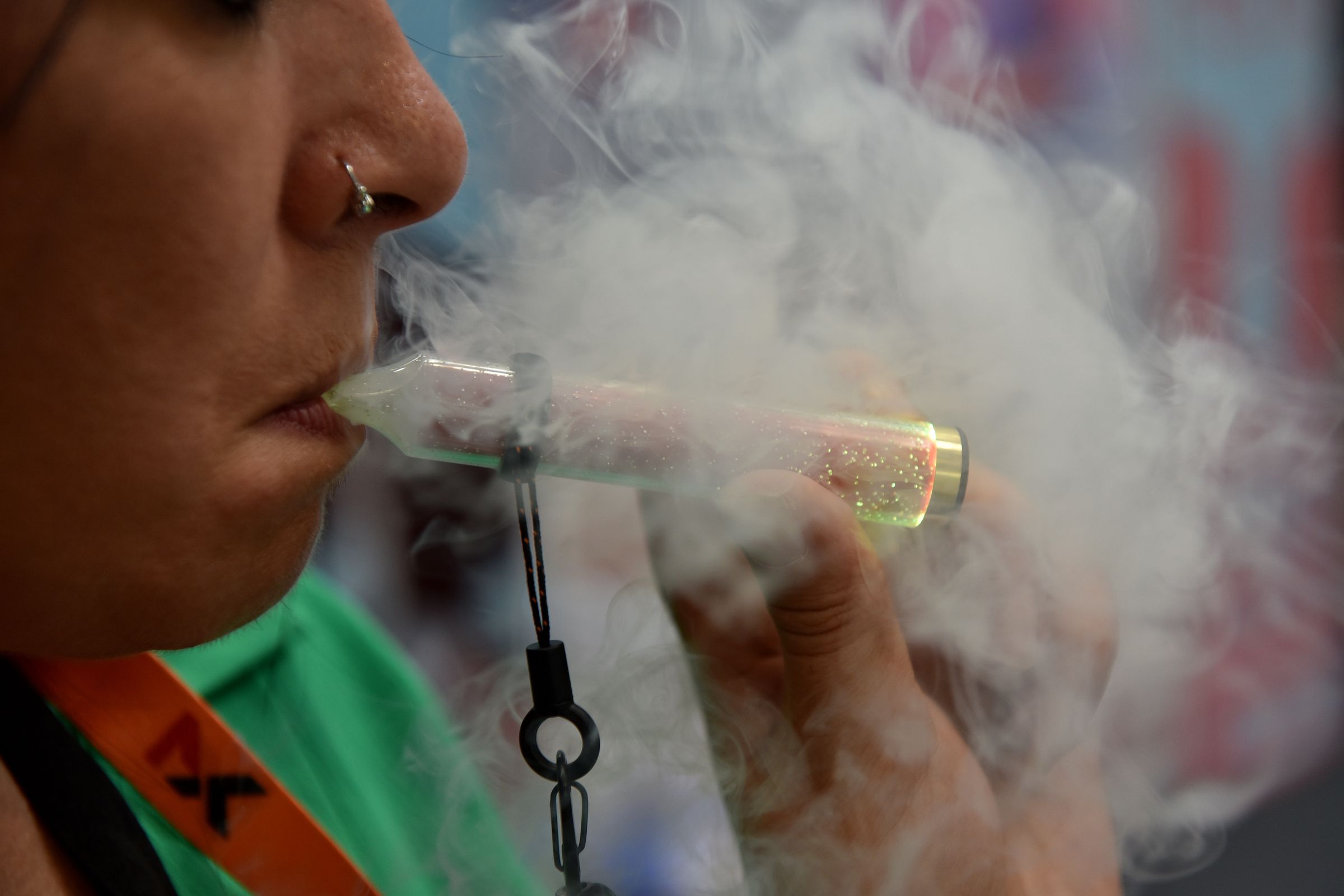 A woman breathes out a cloud of smoke from a vaporizer.