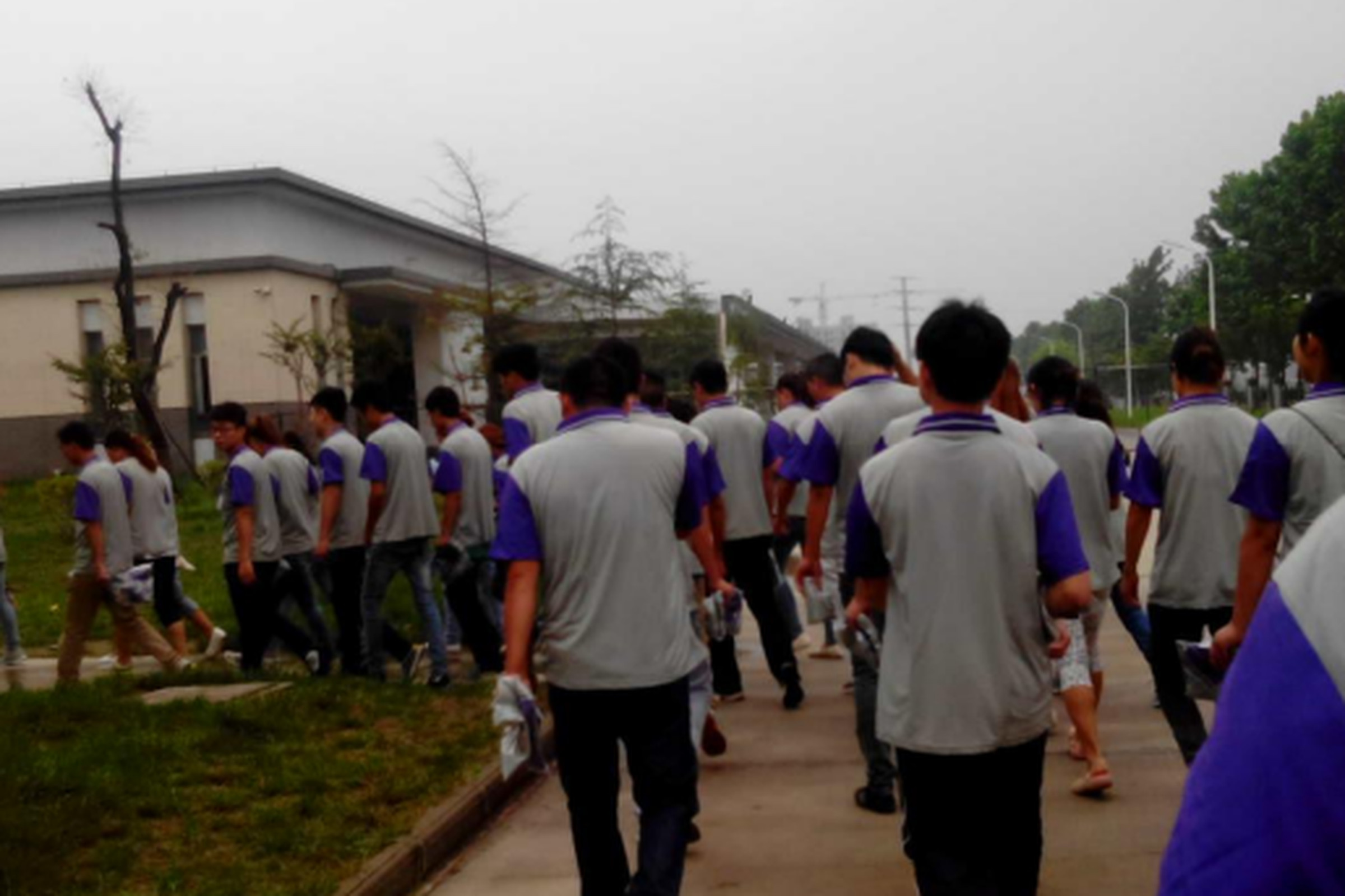 Workers in Suqian, China, assemble at a Catcher Technology factory accused of labor rights violations
