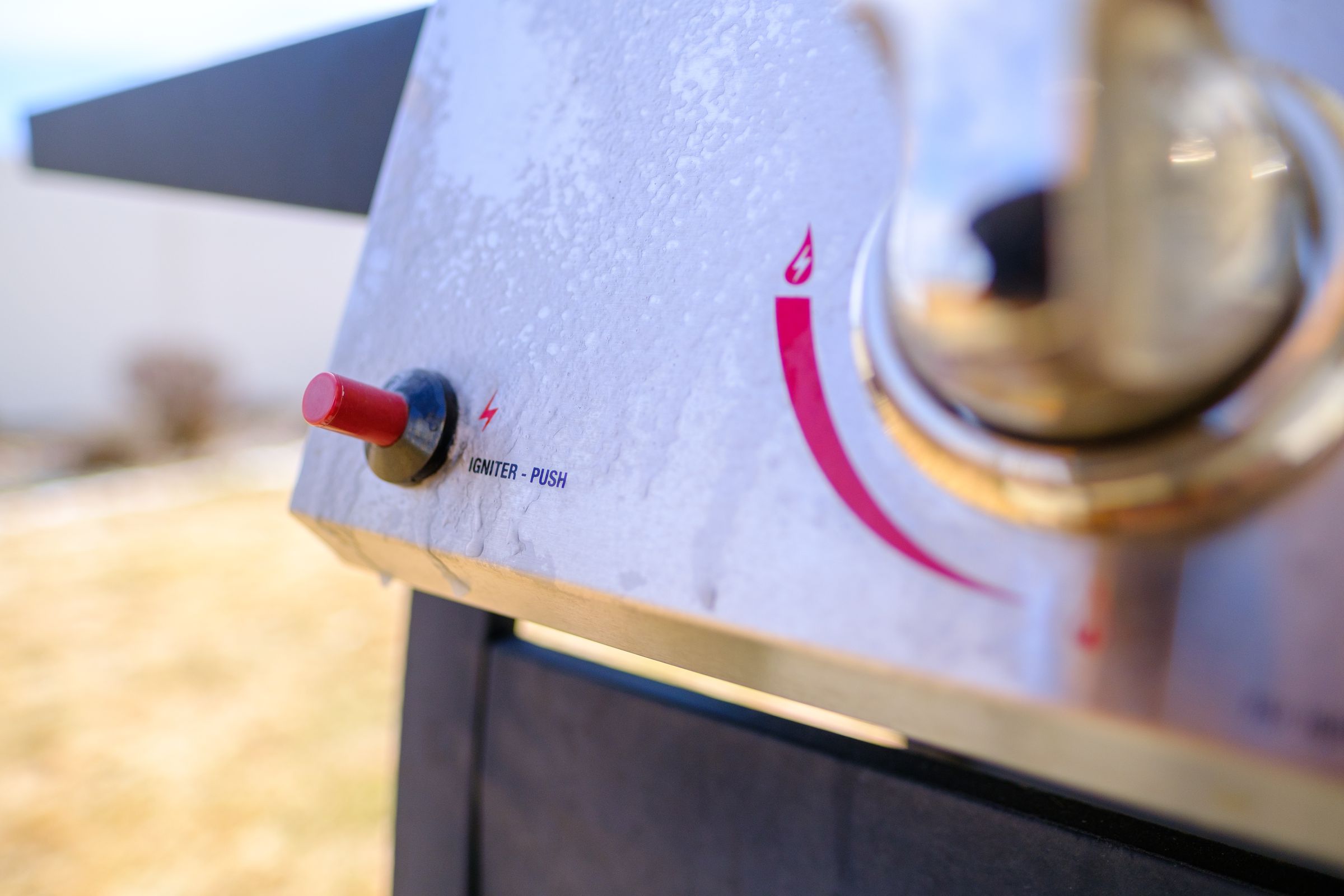 Picture of a red ignition button on an ice-encrusted grill.