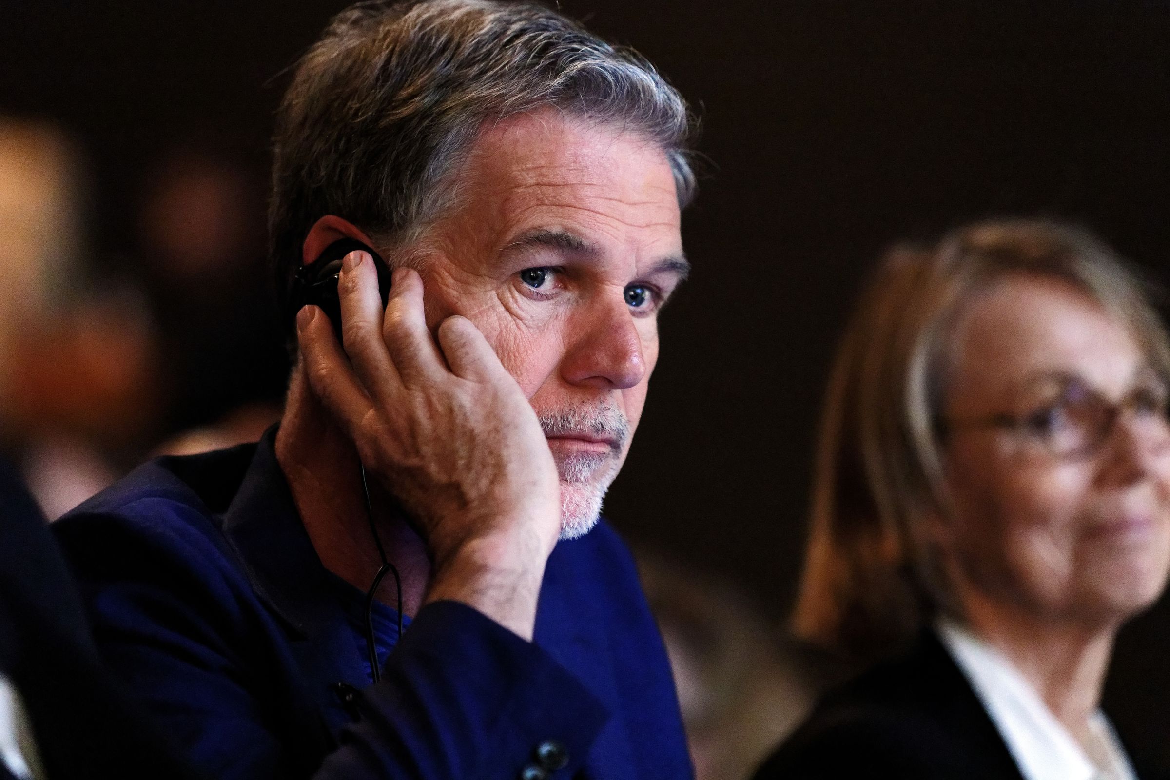 Netflix CEO Reed Hastings at a conference, with a concerned expression