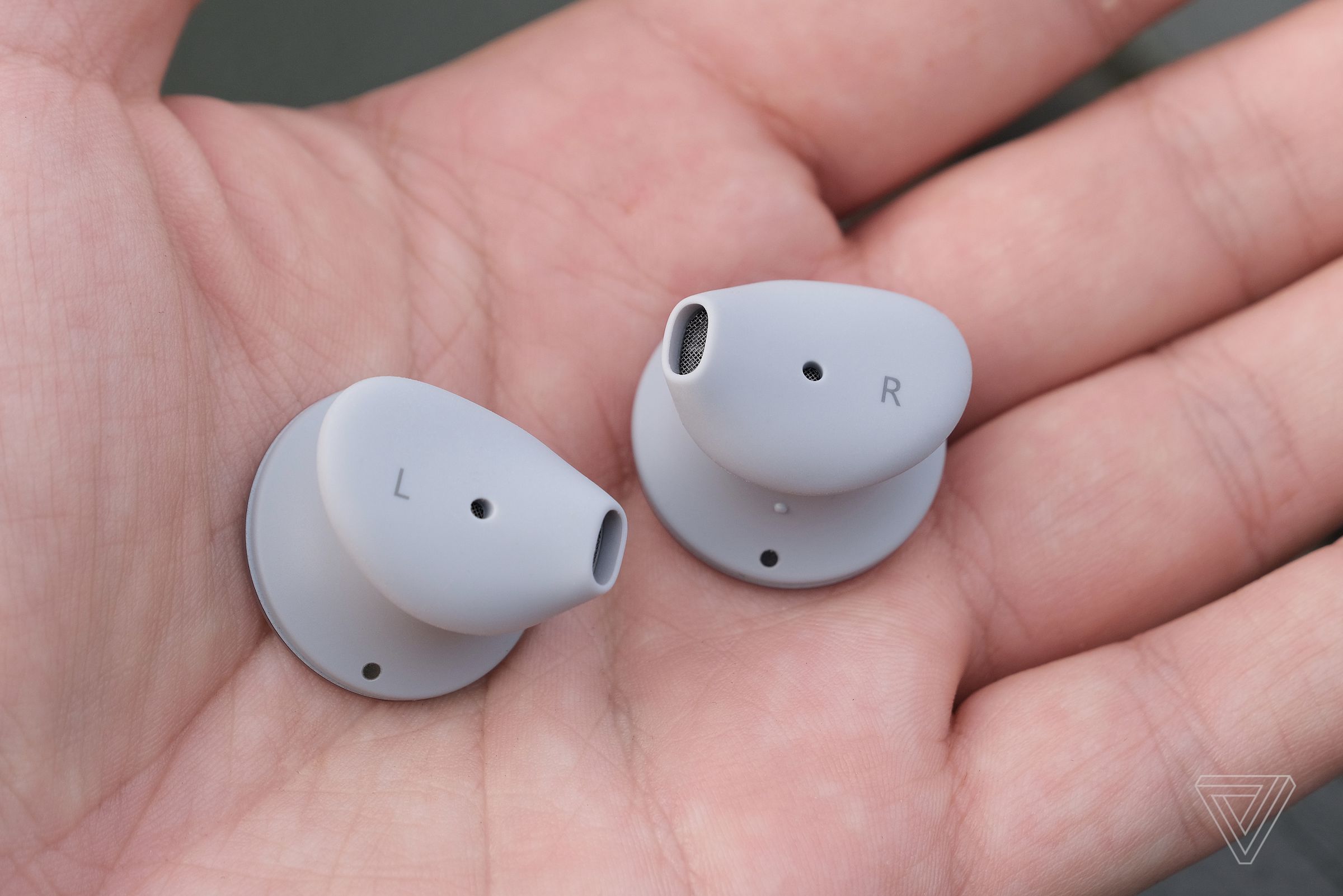 The left and right Surface Earbuds, pictured side by side in a hand.