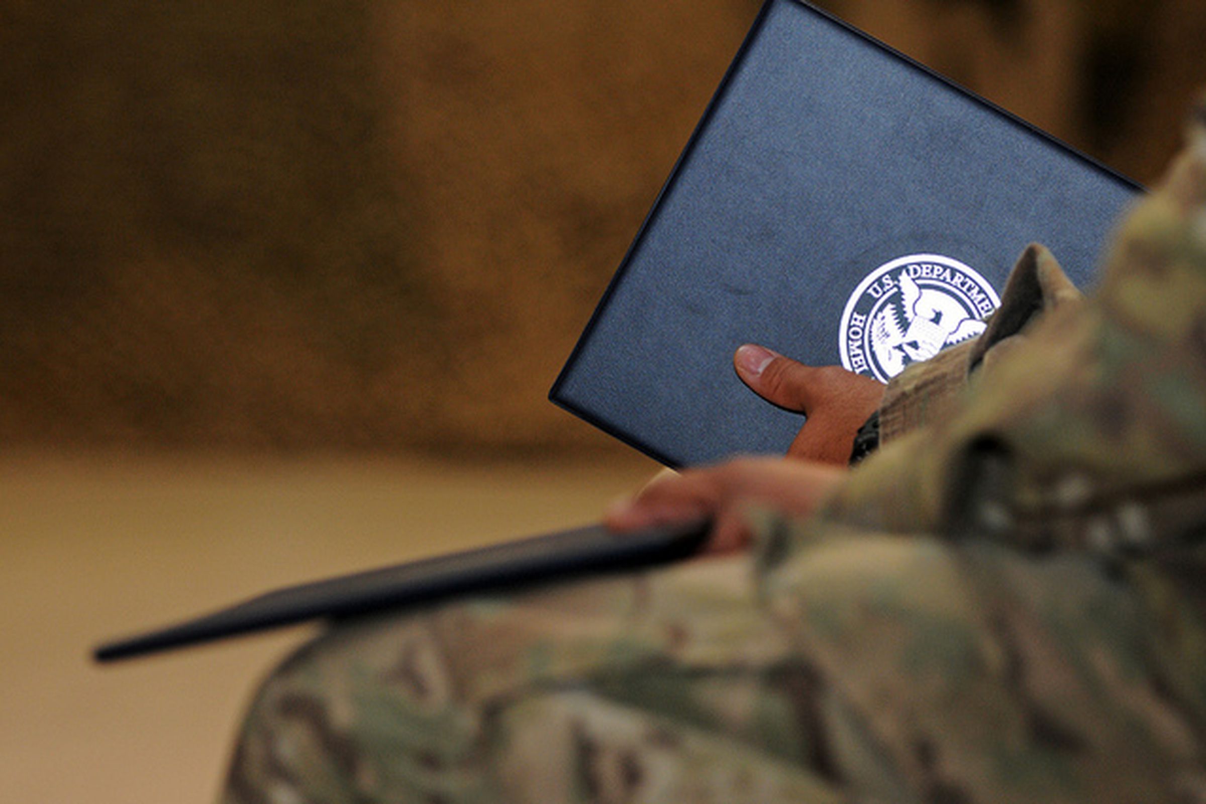 A soldier holds a folder bearing the seal of the US Dept. of Homeland Security