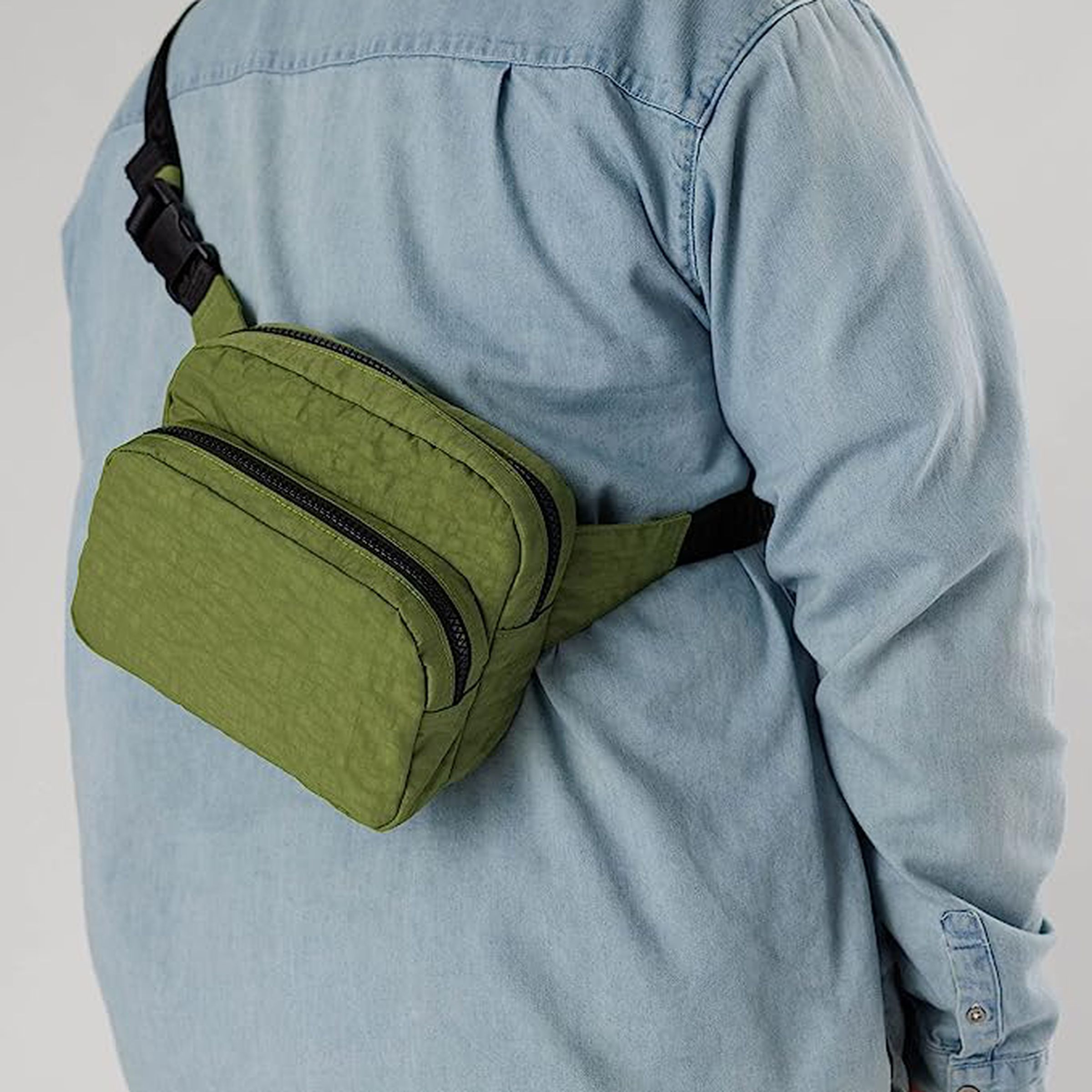 Man wearing fanny pack around the shoulders and slung behind.