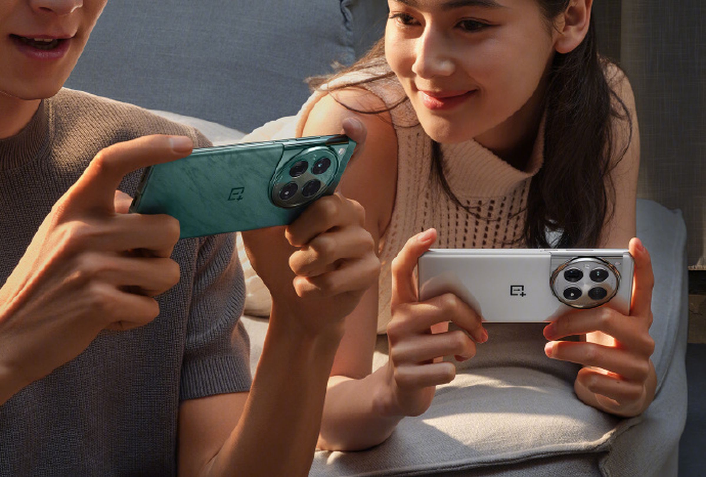 Two people holding the OnePlus 12 mobile phone in green and white.