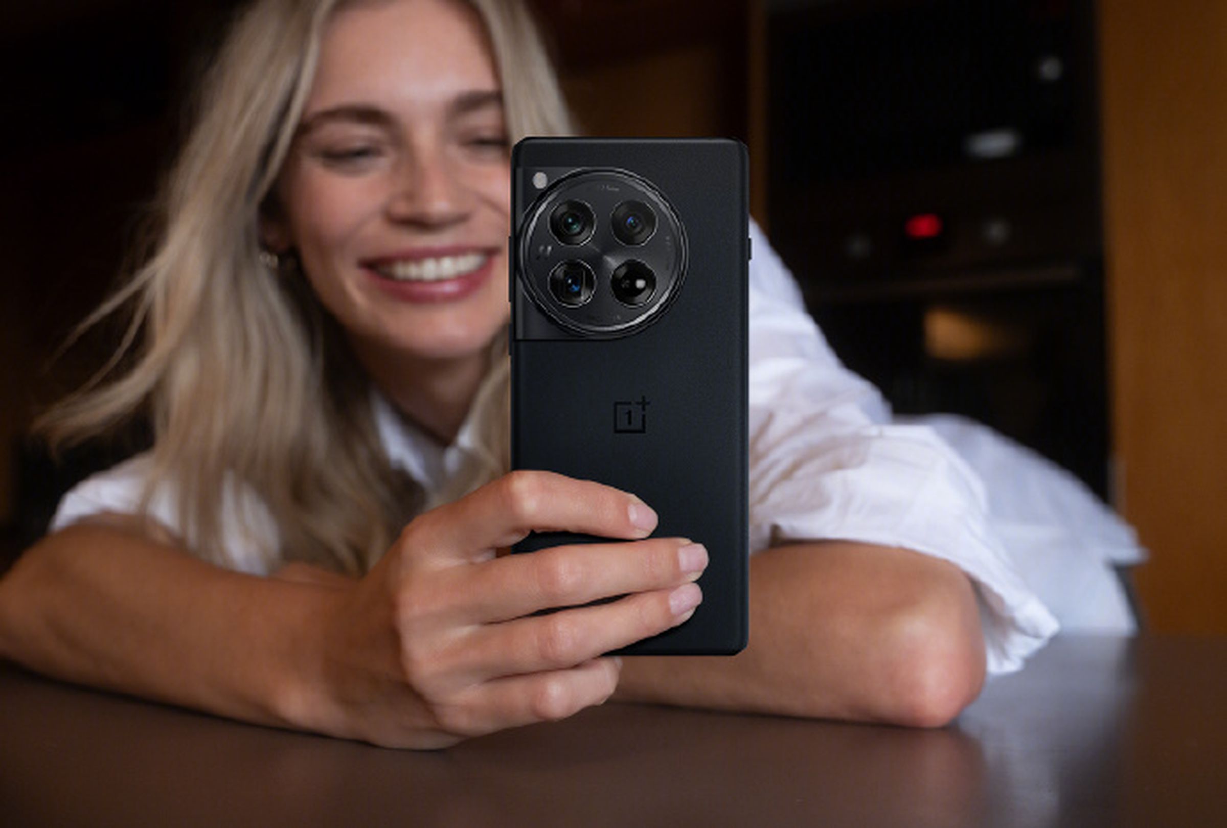A woman holding the OnePlus 12 mobile phone in black.