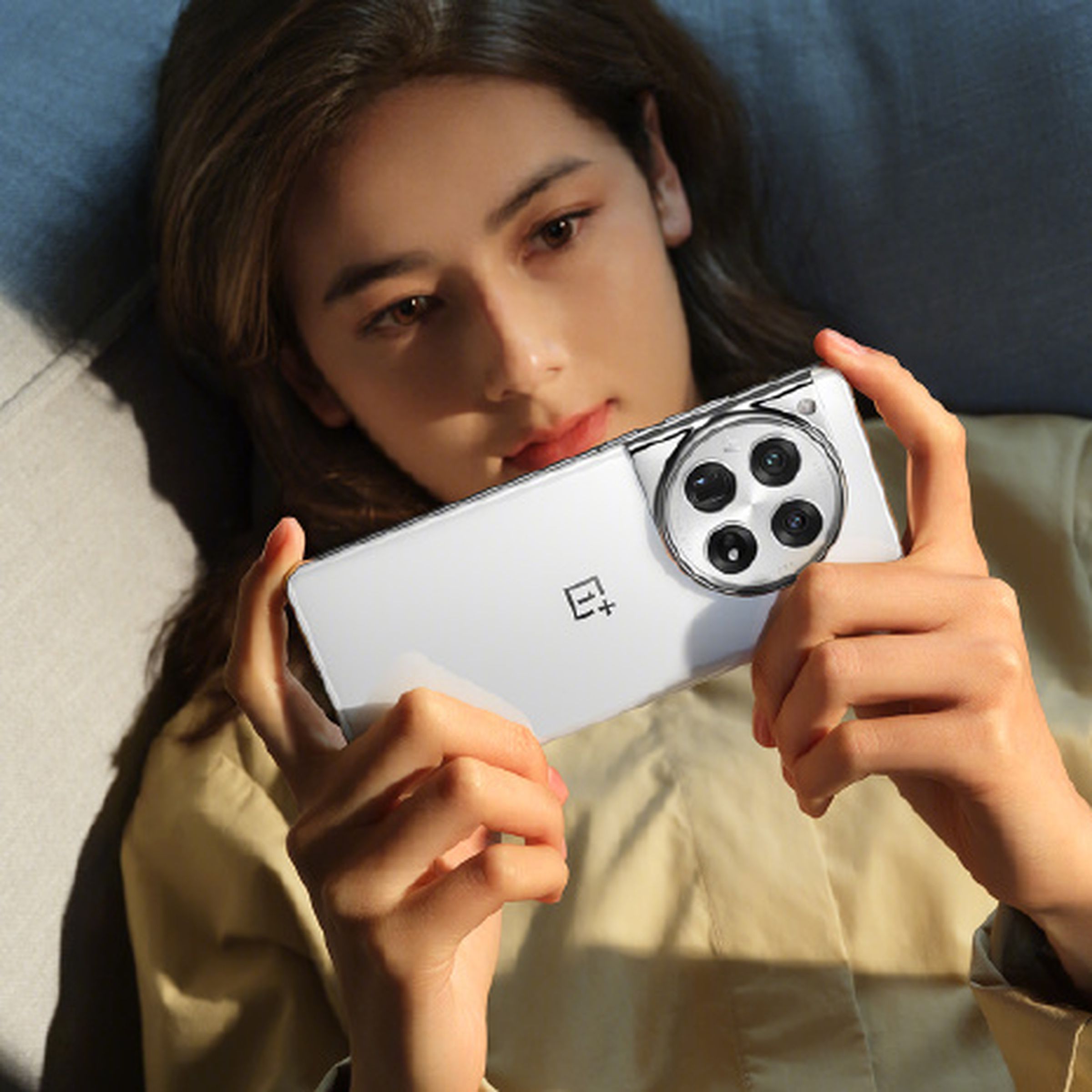 A woman holding the OnePlus 12 phone in white.