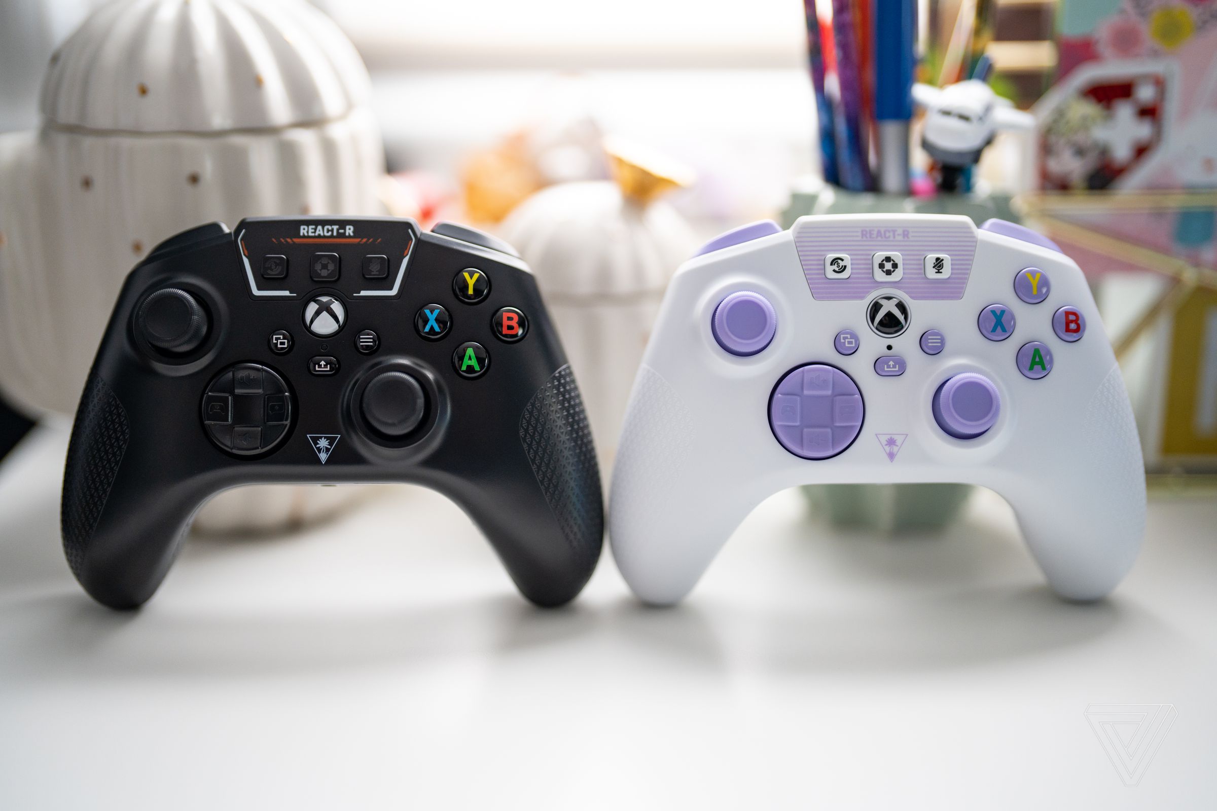 A side-by-side image of the Turtle Beach React-R controllers, black on the left and white / purple on the right.