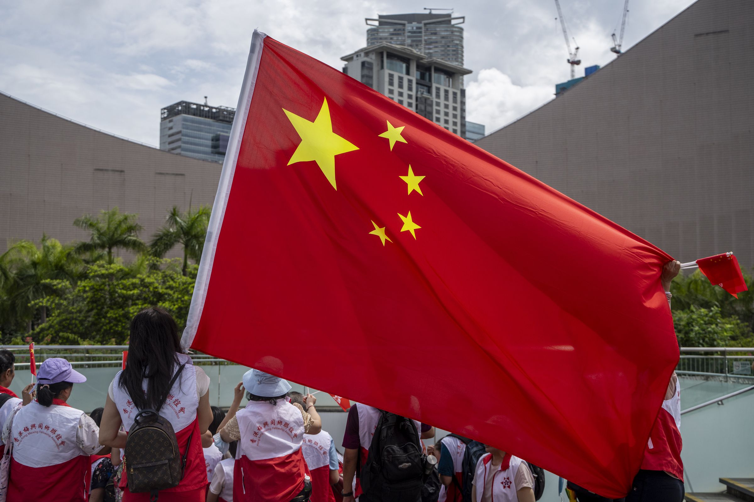 People holding up the National Flag of China in front of the Hong Kong Skyline