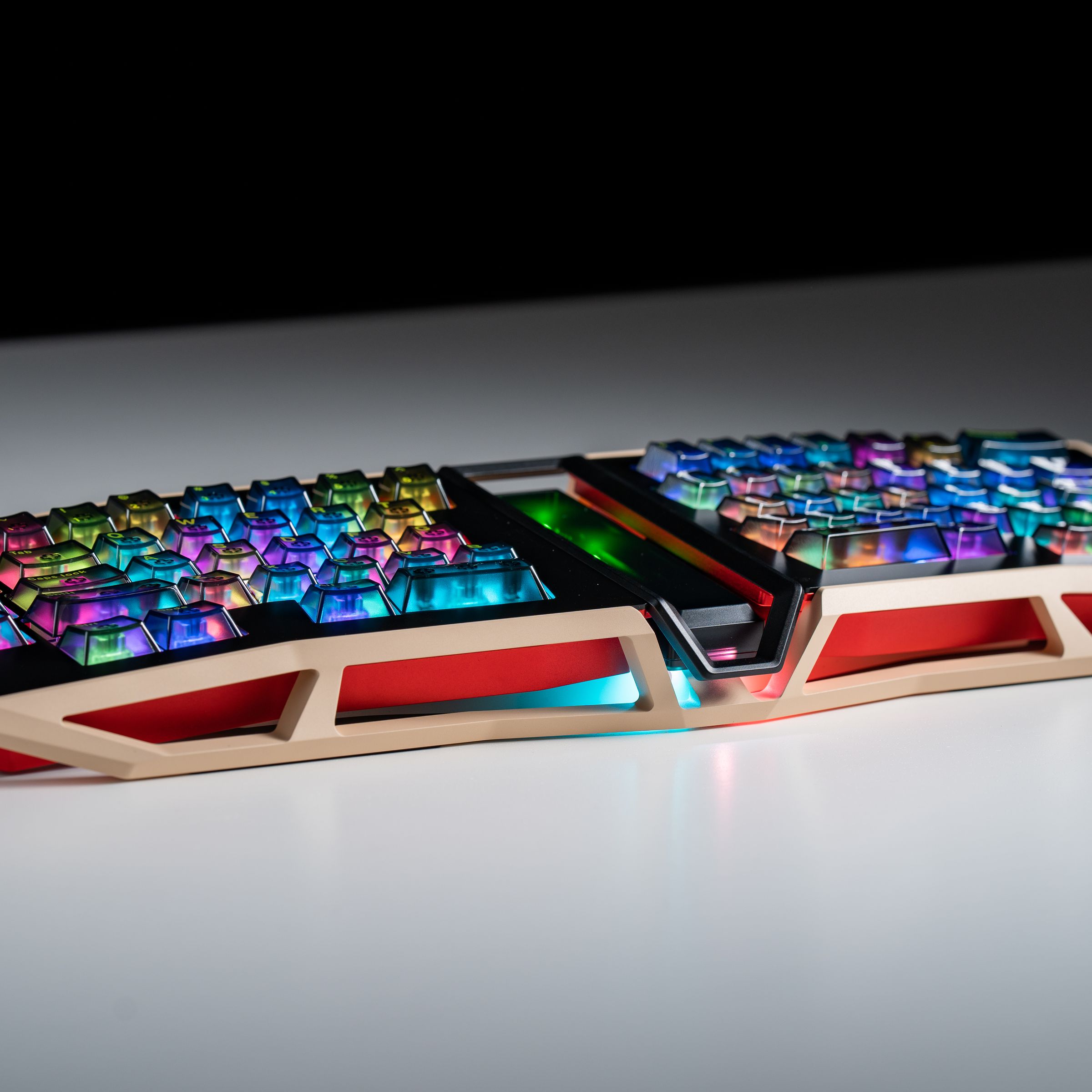 A tan and red ergonomic keyboard with see-through keycaps illuminated by multicolored light, resting on a white table.