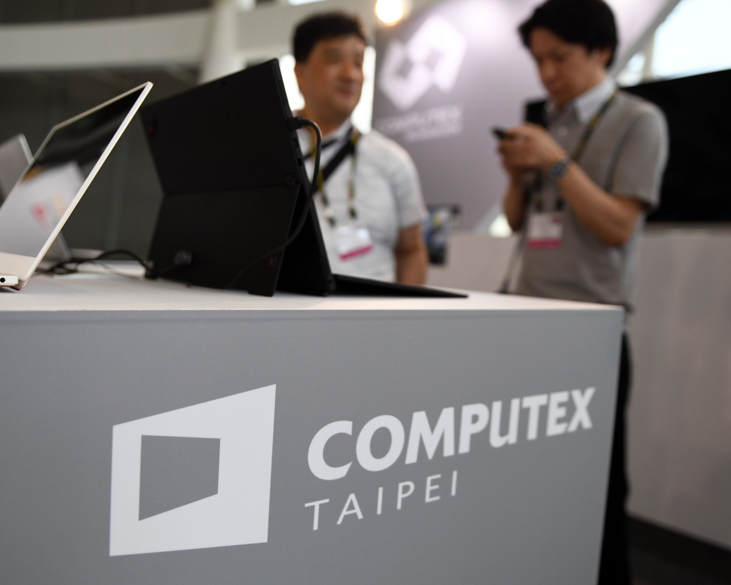 Two visitors stand behind a desk with Computex logo during Computex 2018 at the Nangang Exhibition Center in Taipei.