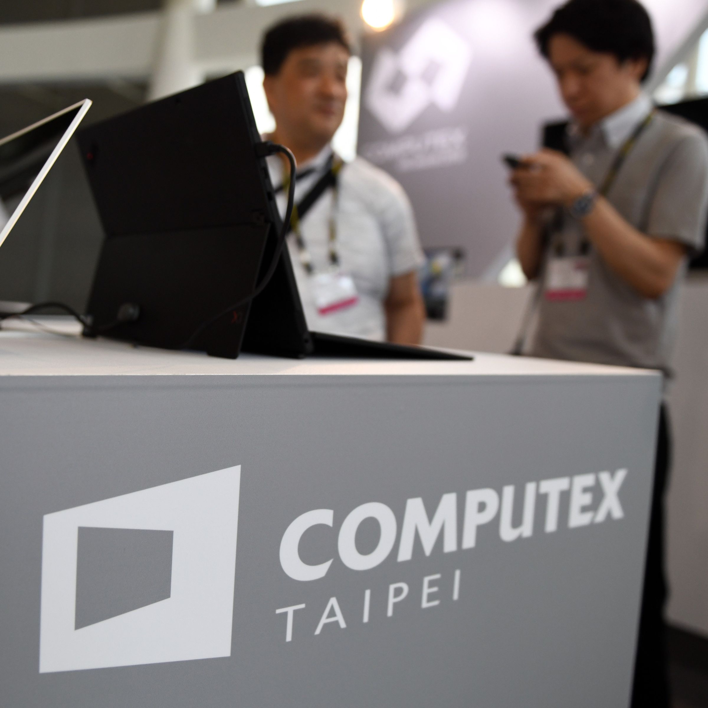 Two visitors stand behind a desk with Computex logo during Computex 2018 at the Nangang Exhibition Center in Taipei.