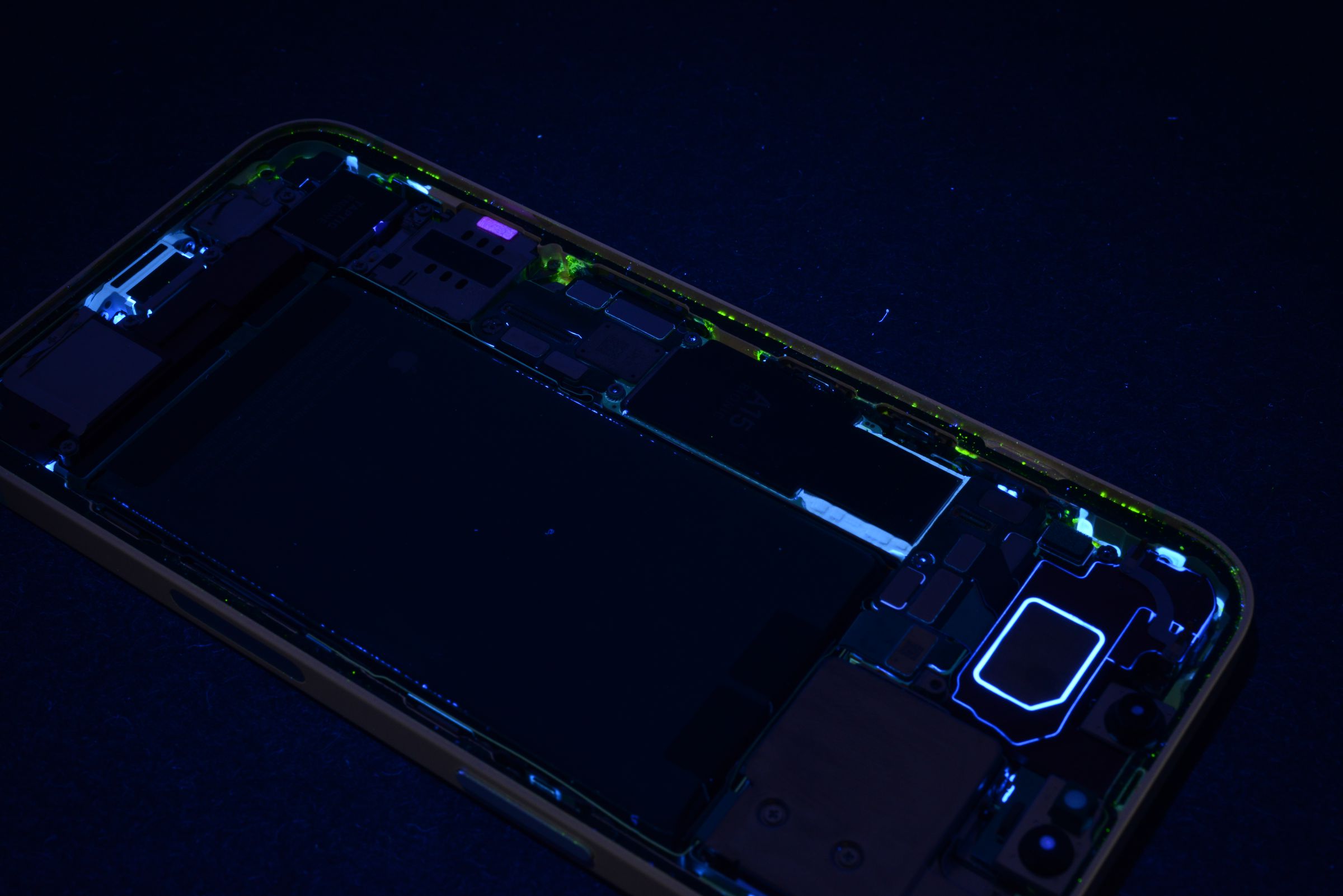 A UV-lit shot of an iPhone, showing water residue around the edges.