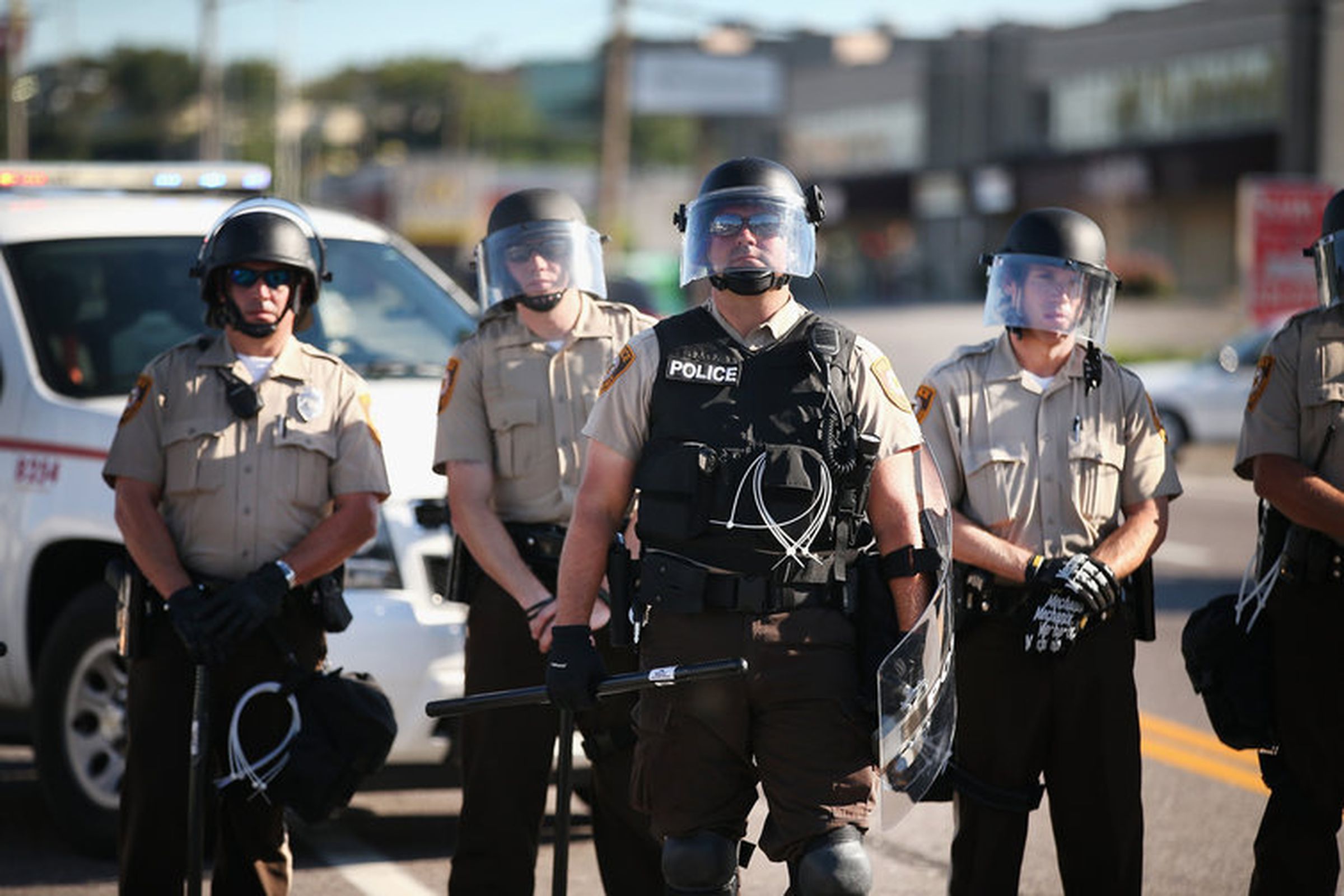 Police watch as demonstrators protest the shooting death of teenager Michael Brown in Ferguson, Missouri. 