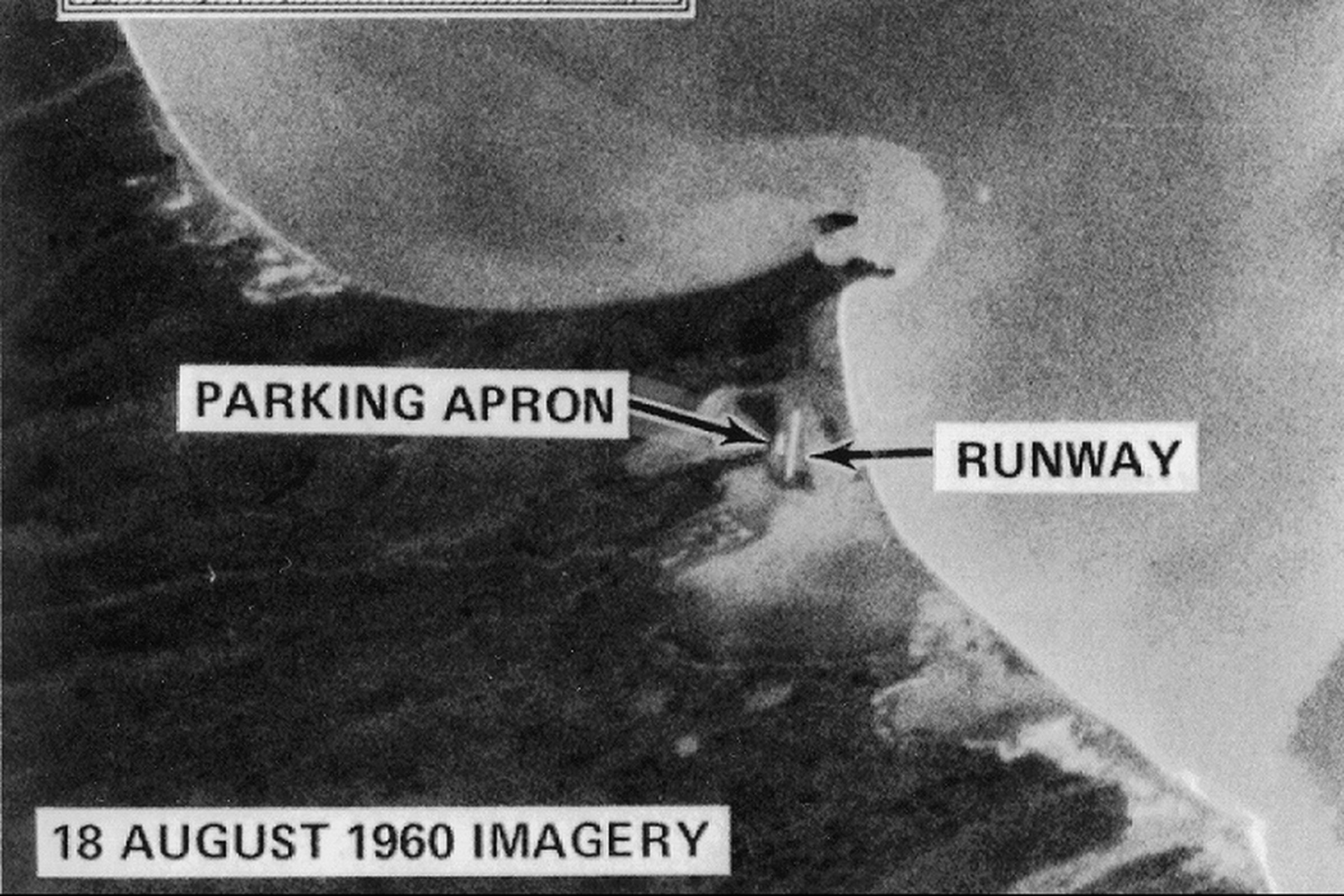 A black and white satellite photo of an area in Russia, with text that says “18 August 1960 Imagery.” There are arrows pointing to areas that say “Parking Apron” and “Runway.”