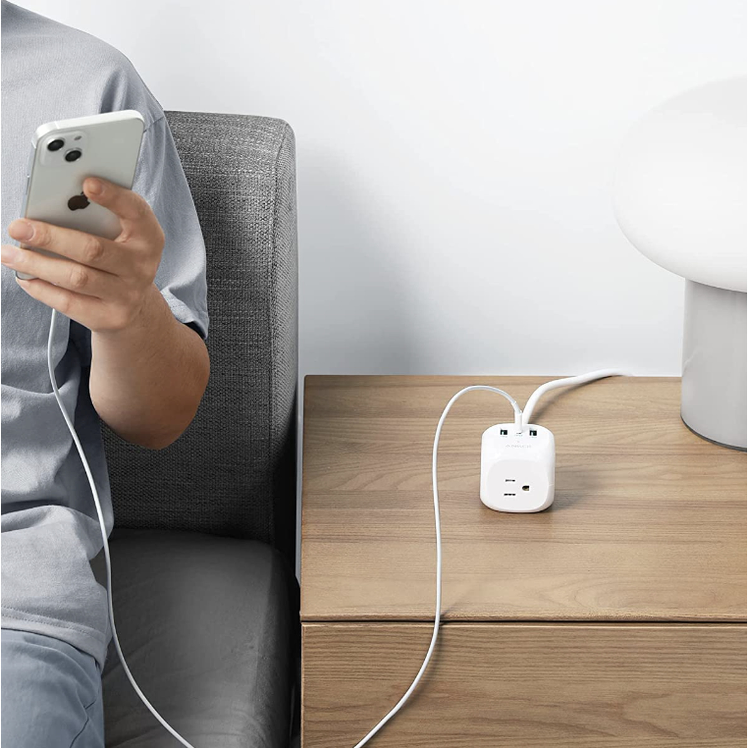 Anker cube power strip on table in between a person with a phone and a computer
