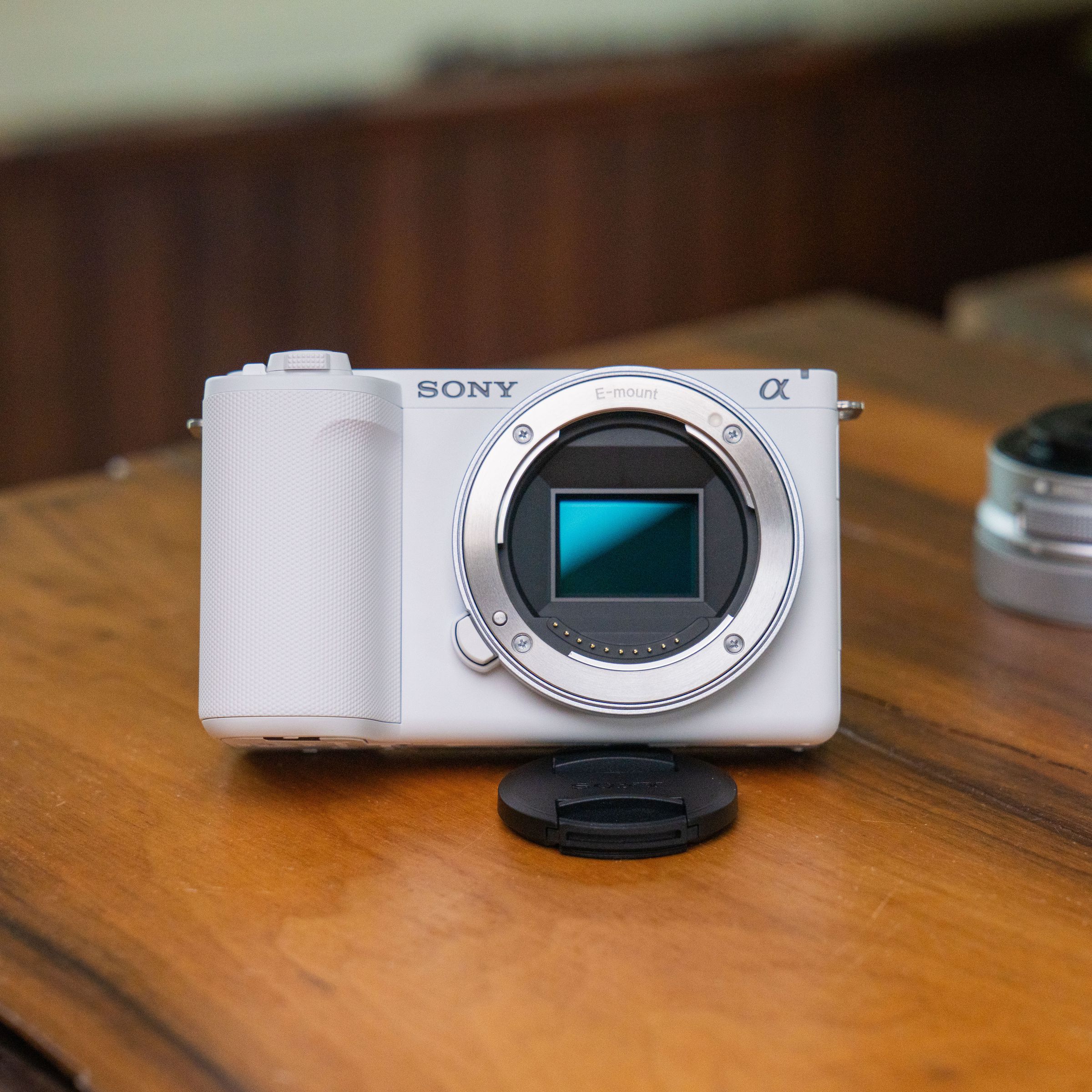 The Sony ZV-E10 II in white, sitting on a table with its lens detached.