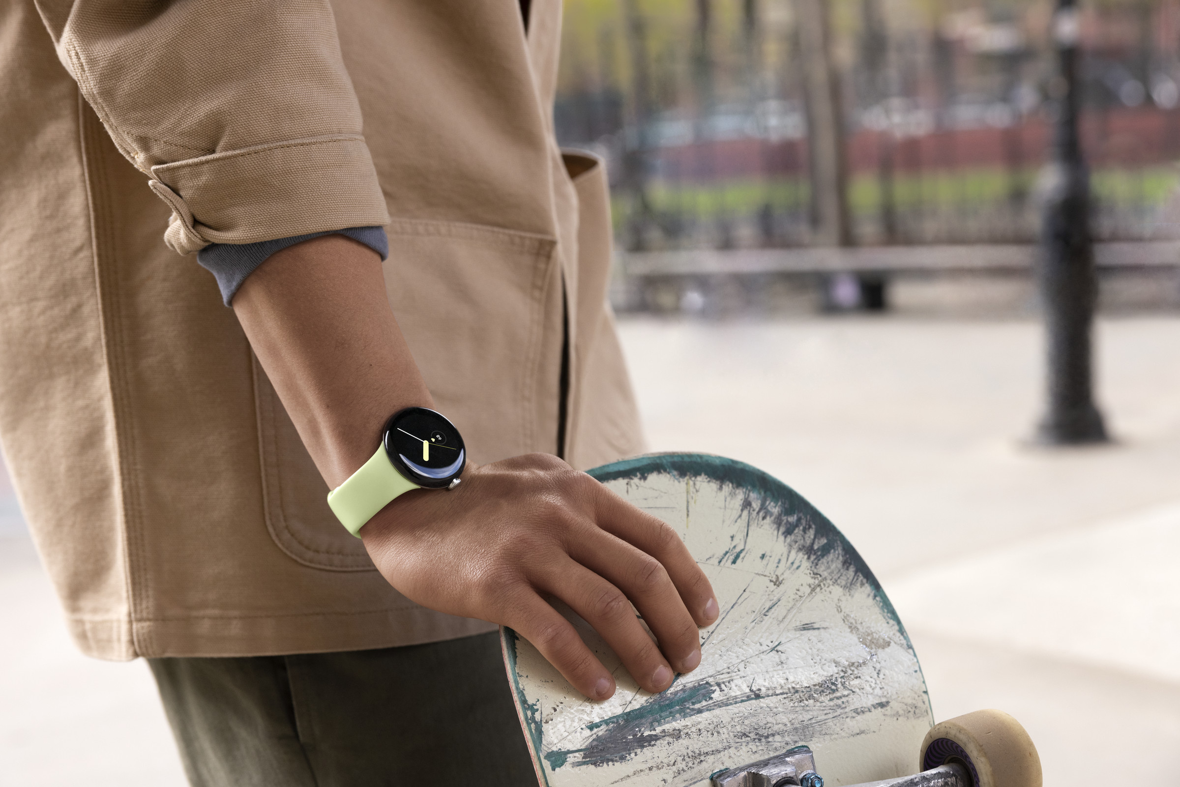 The Lemongrass Pixel Watch on a wrist of someone at a skate park.