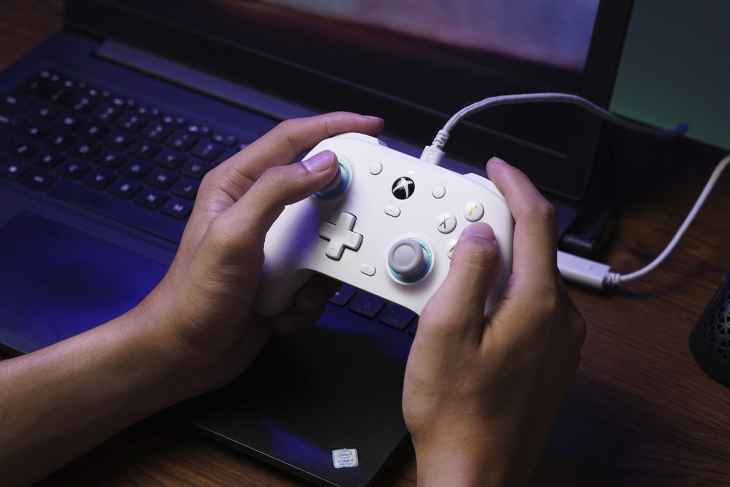 A pair of hands playing a white GameSir G7 SE controller on a laptop.