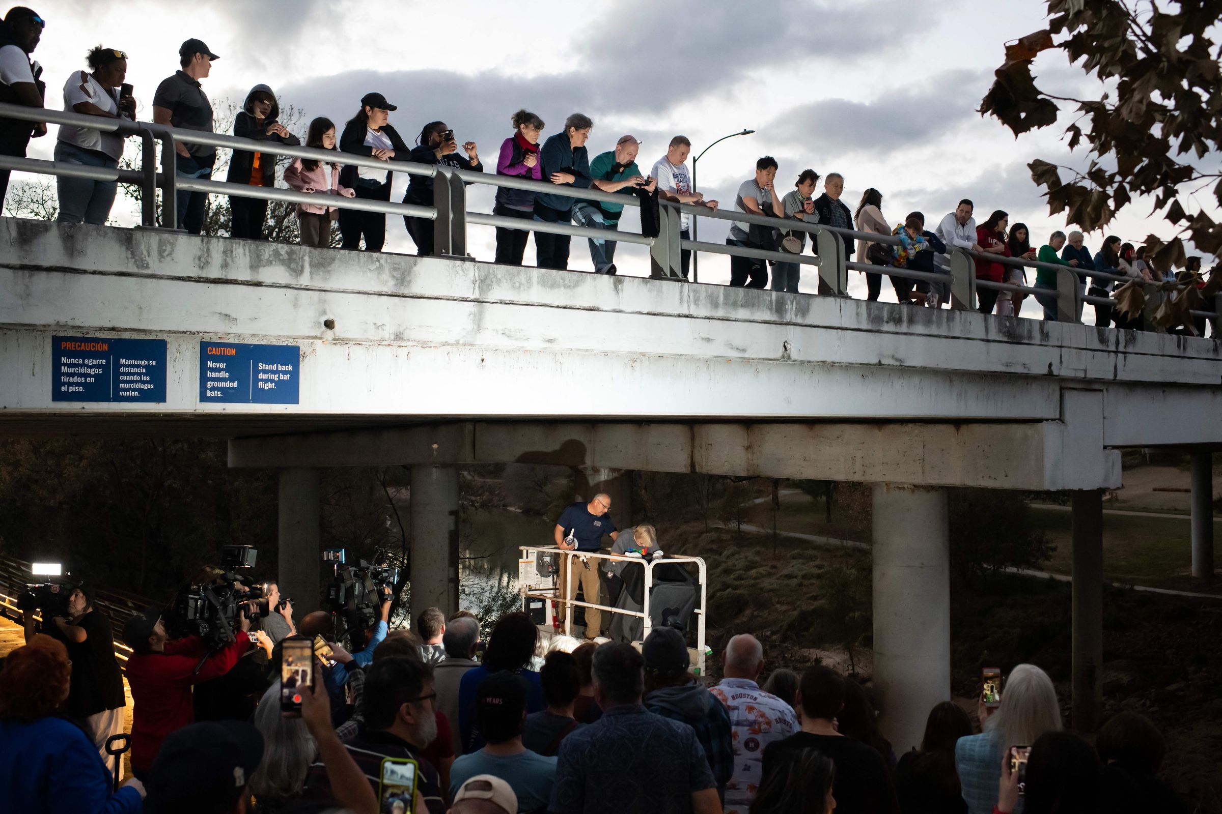 Crowds gathered atop and below a bridge.