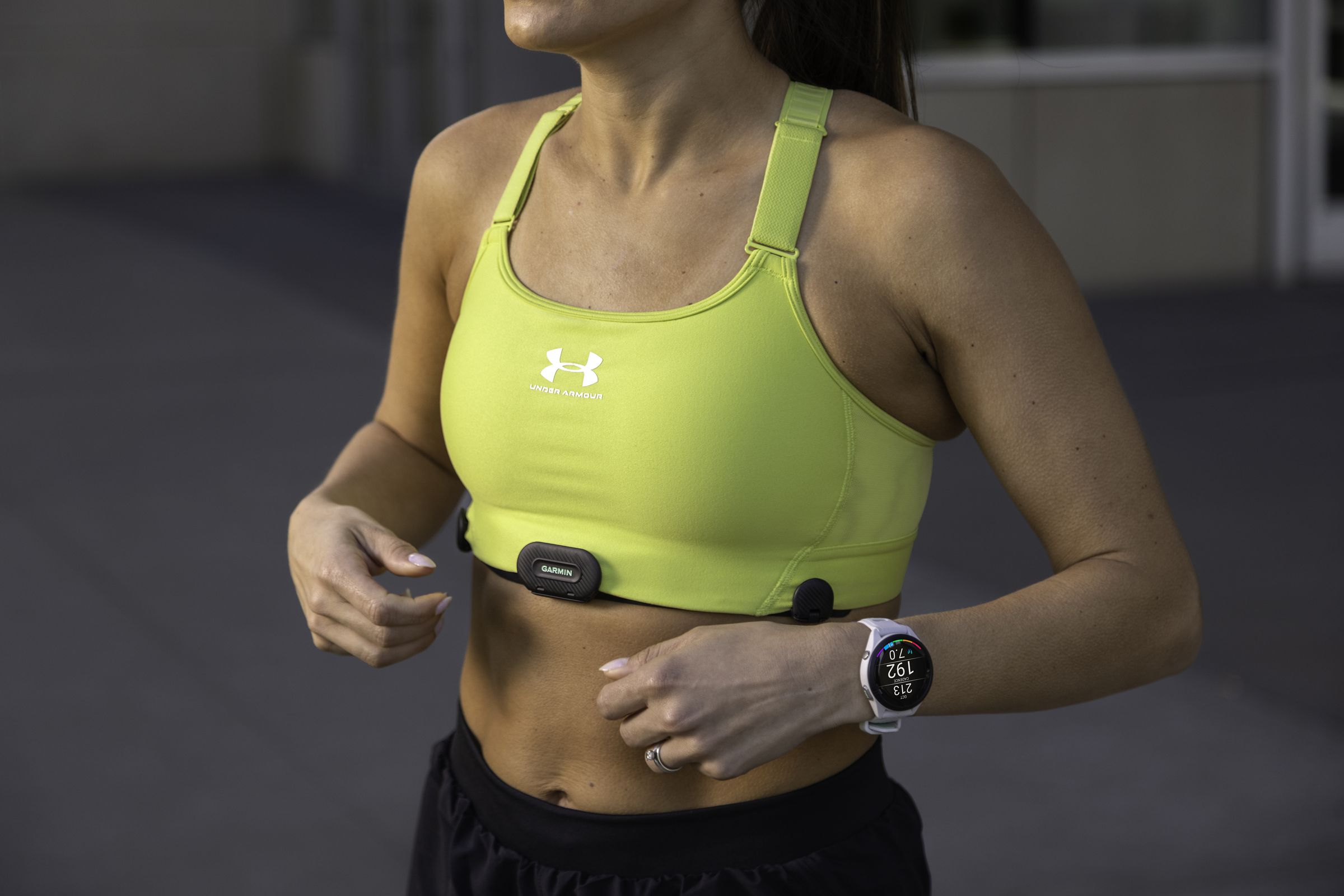 Woman modeling Garmin HRM-Fit chest strap, which clips onto the bottom of sports bras.