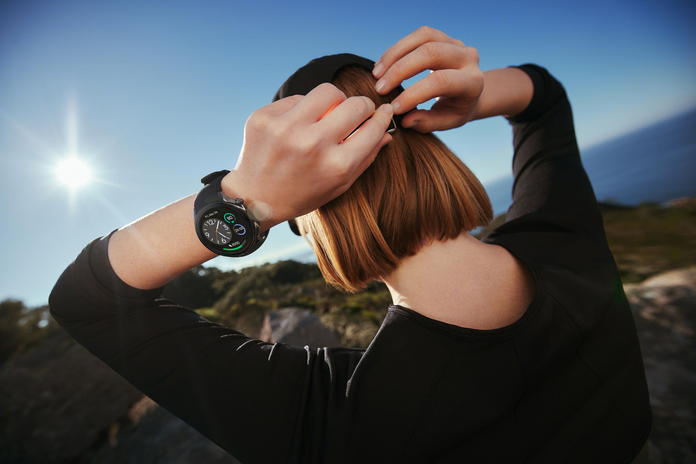 A person wearing a OnePlus Watch 2 while tying their hair