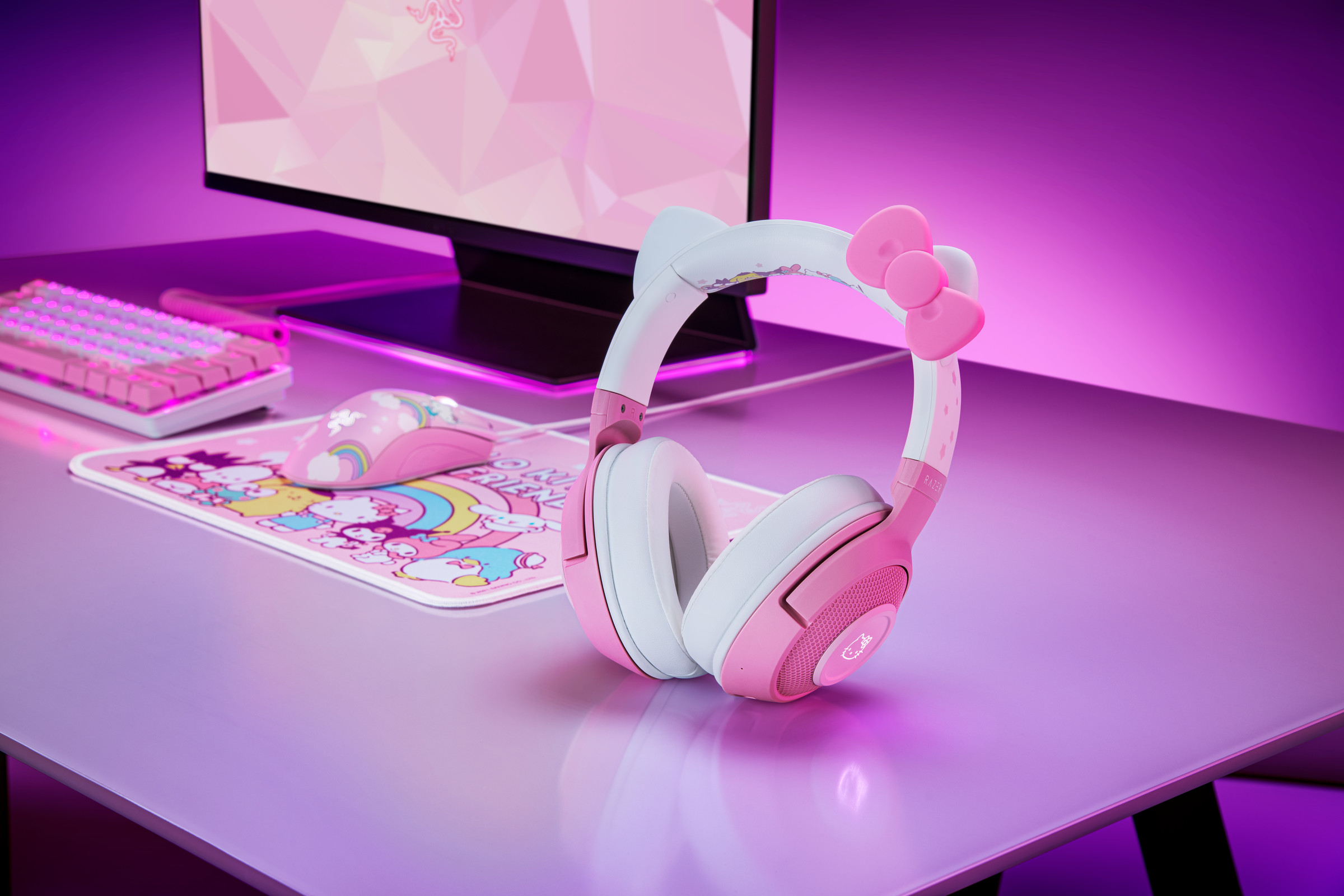 Razer’s Hello Kitty headset on a pink table with a pink keyboard, mousepad, and monitor in the background.