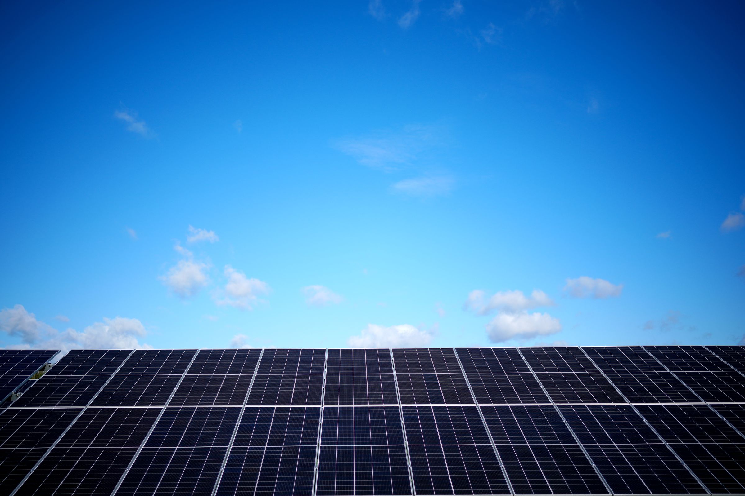 A row of solar panels below a blue sky.