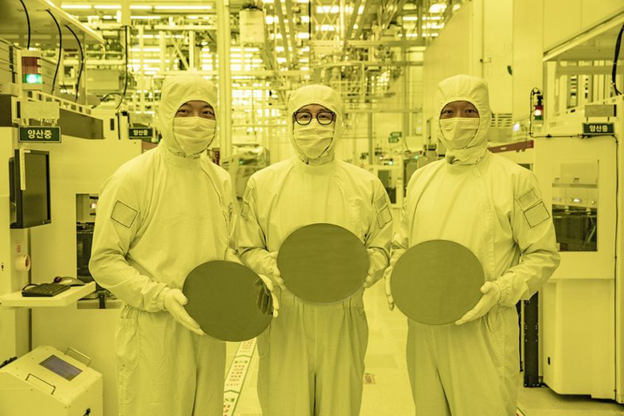Samsung employees hold up 3nm wafers at the company’s production line
