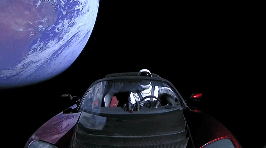 The tesla roadster floats through space with a mannequin behind the wheel.