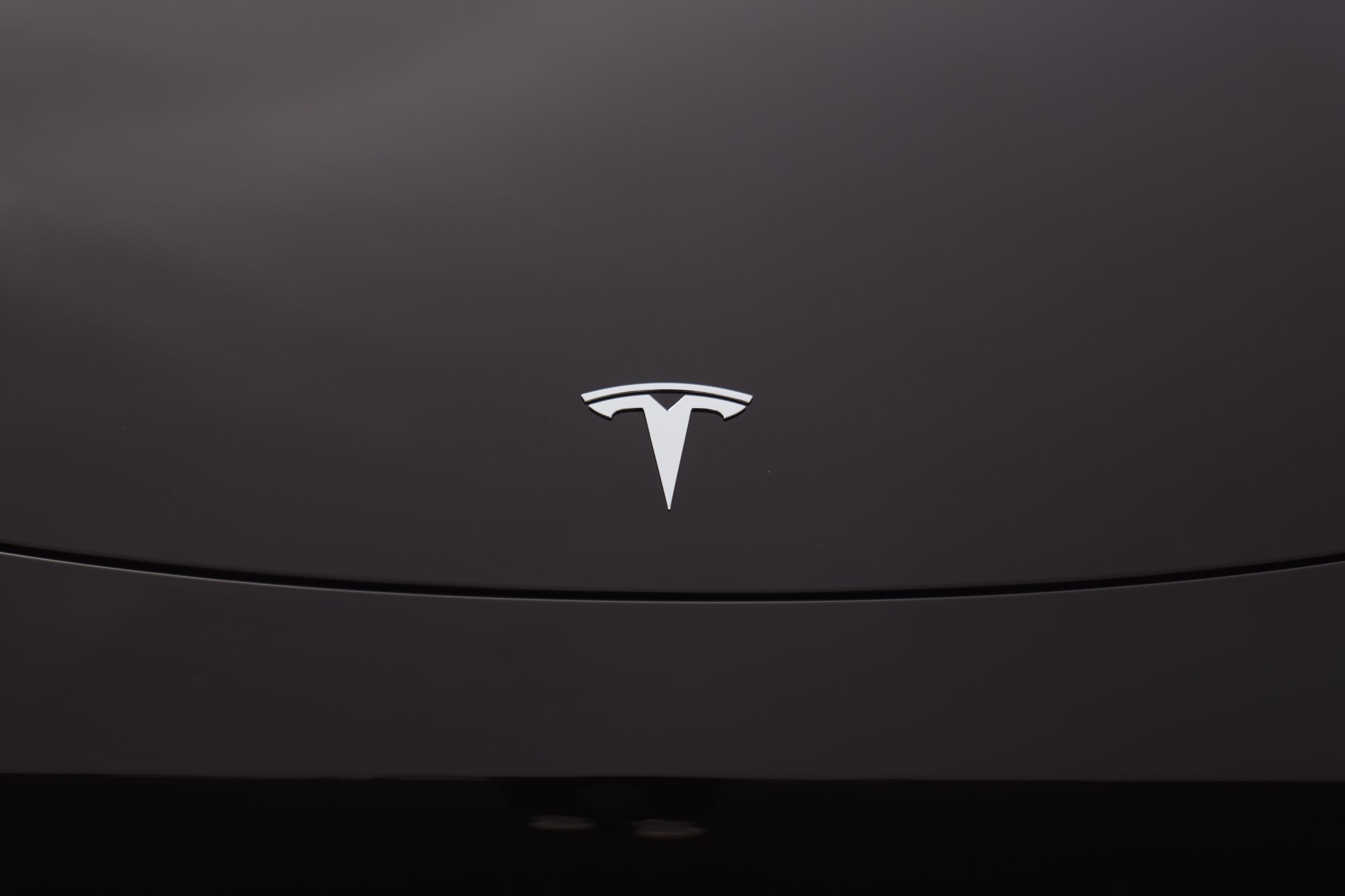 An image showing the Tesla logo on a black vehicle