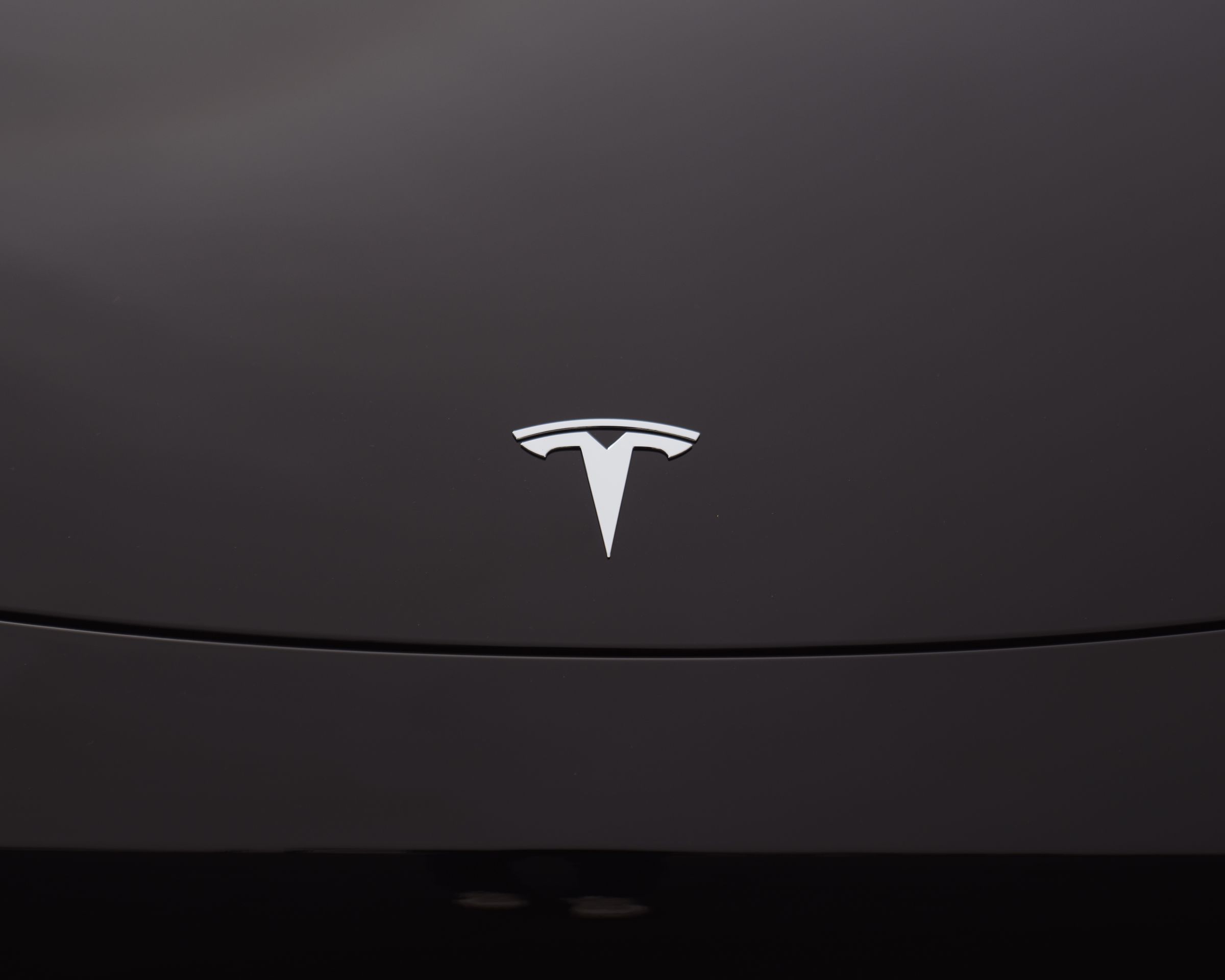 An image showing the Tesla logo on a black vehicle