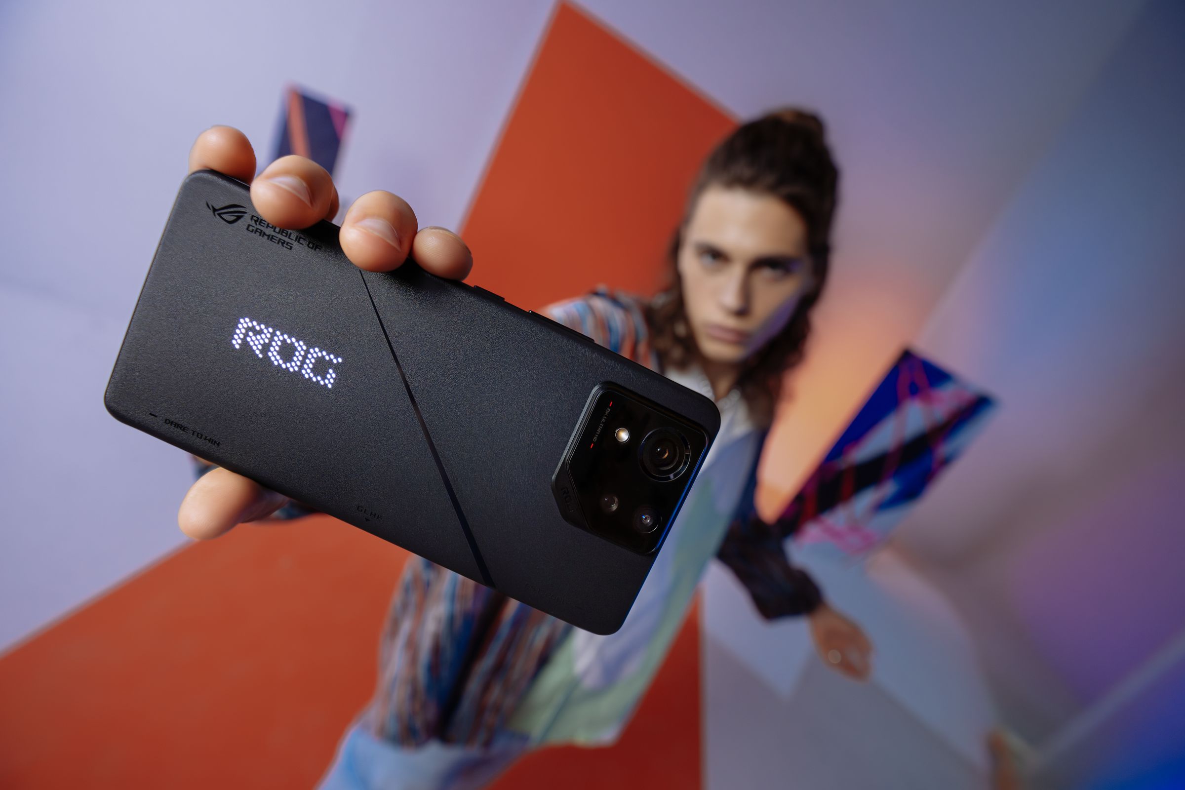 Model holds up ROG Phone 8 to camera.