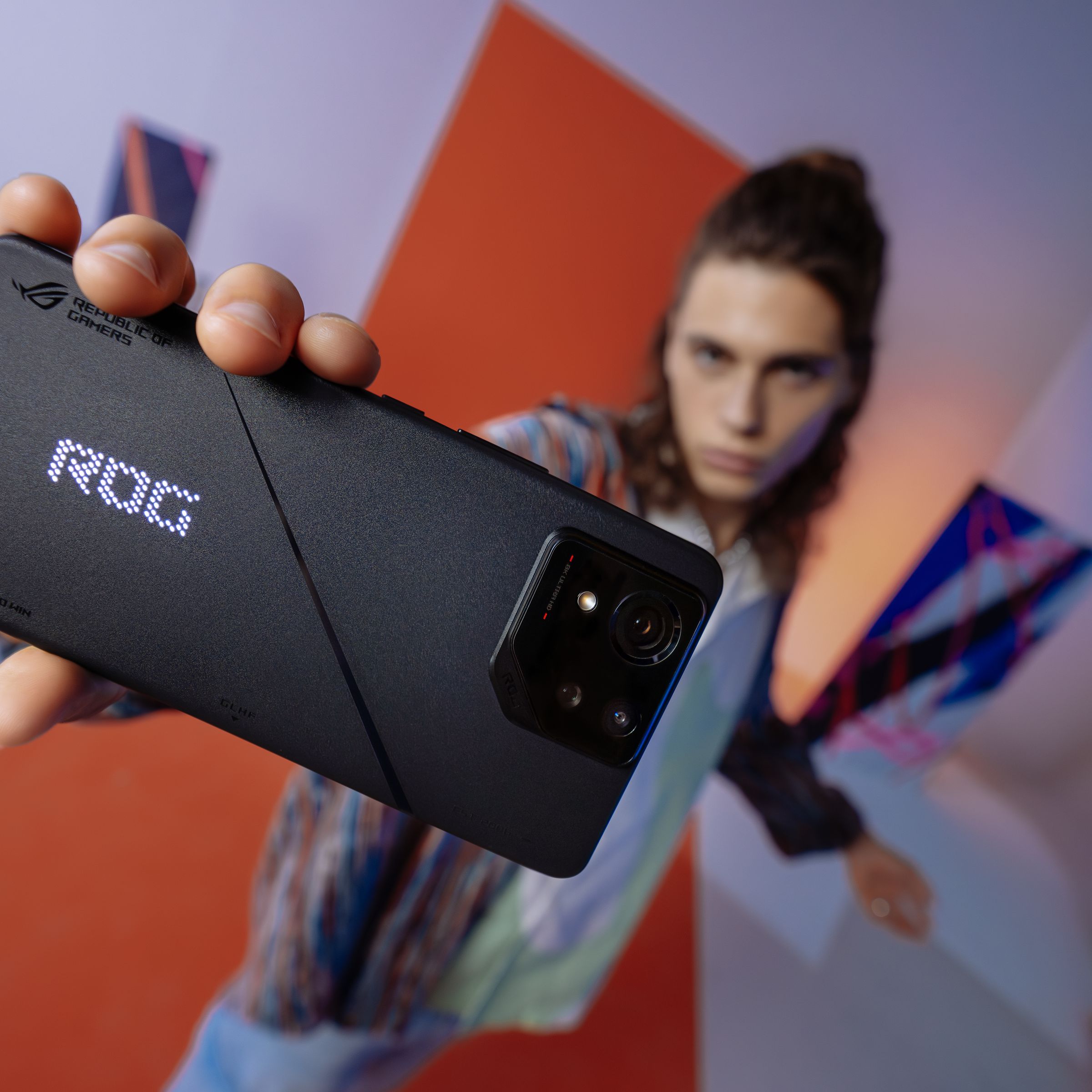 Model holds up ROG Phone 8 to camera.