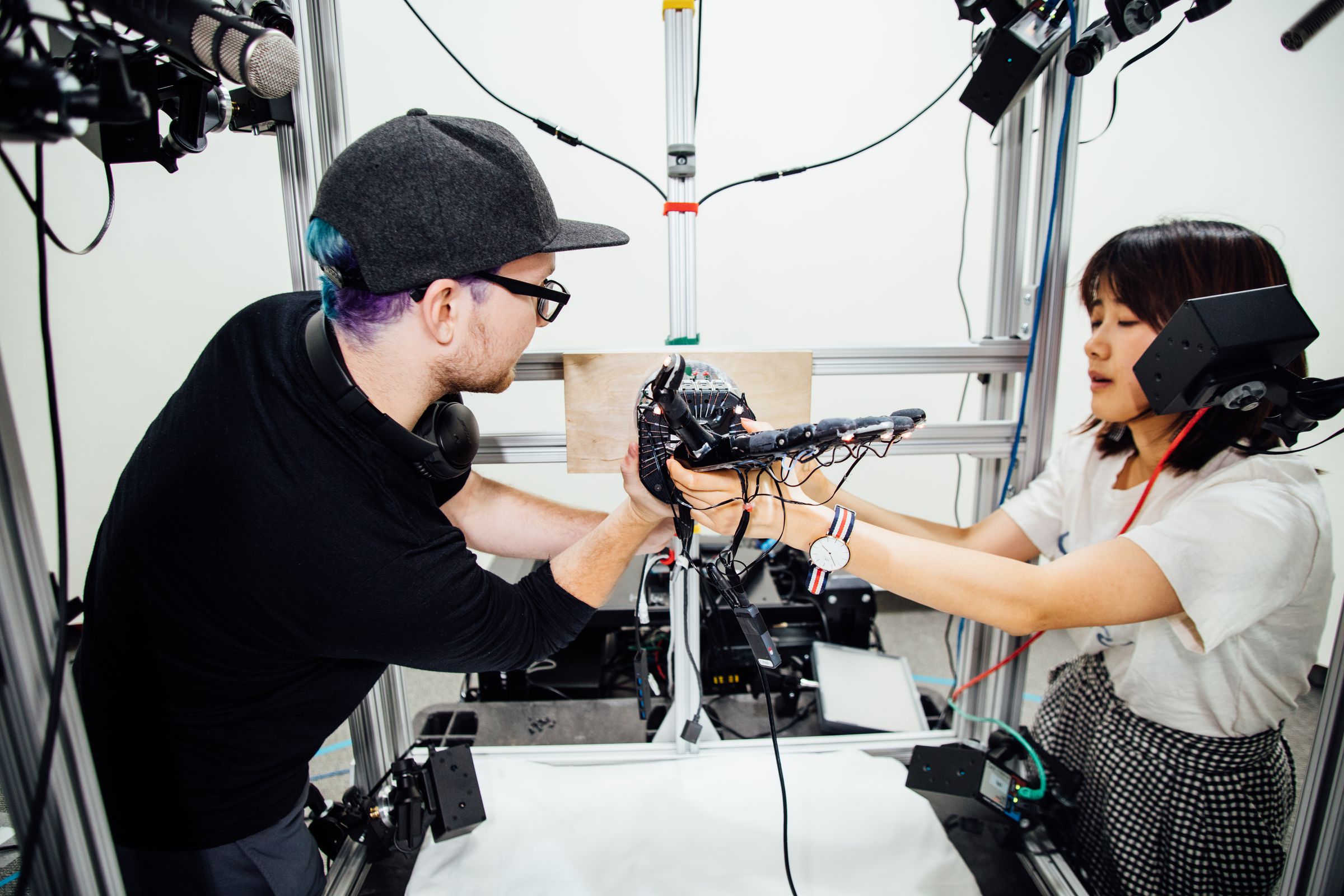OpenAI’s researchers adjust the robotic hand controlled by their AI system Dactyl.