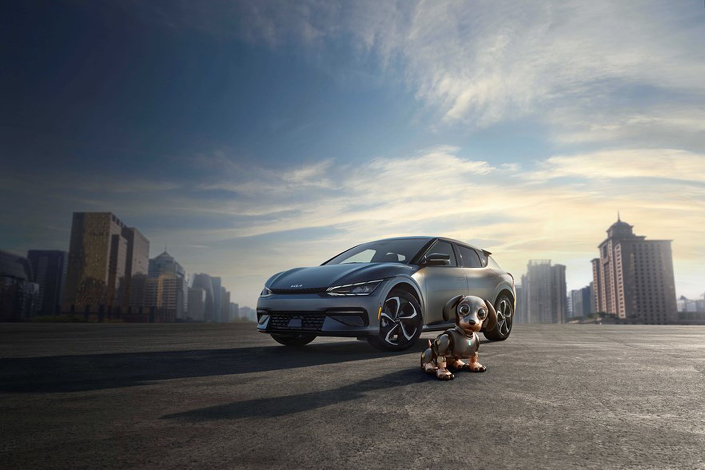 The Kia EV6 pictured with a city backdrop and small robot dog in the foreground. Kia is just starting production of the car, but it won’t be available for weeks or months to come.